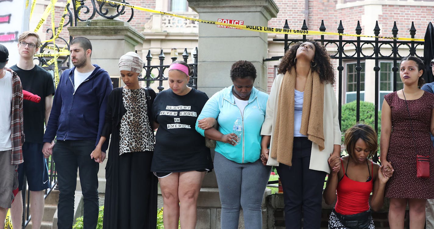 People holds hands outside Gov. Mark Dayton's mansion as Rev. Brian Herron prays during a gathering in response to the shooting of Philander Castile by a police officer Wednesday in Falcon Heights and seen Thursday, July 7, 2016, in St. Paul, MN. Philando Castile, 32, a St. Paul schools employee, was shot by a police officer following a traffic stop in Falcon Heights, MN. Castile later died Wednesday night at HCMC.] (DAVID JOLES/STARTRIBUNE)djoles@startribune Protesters at Governor's mansion aft