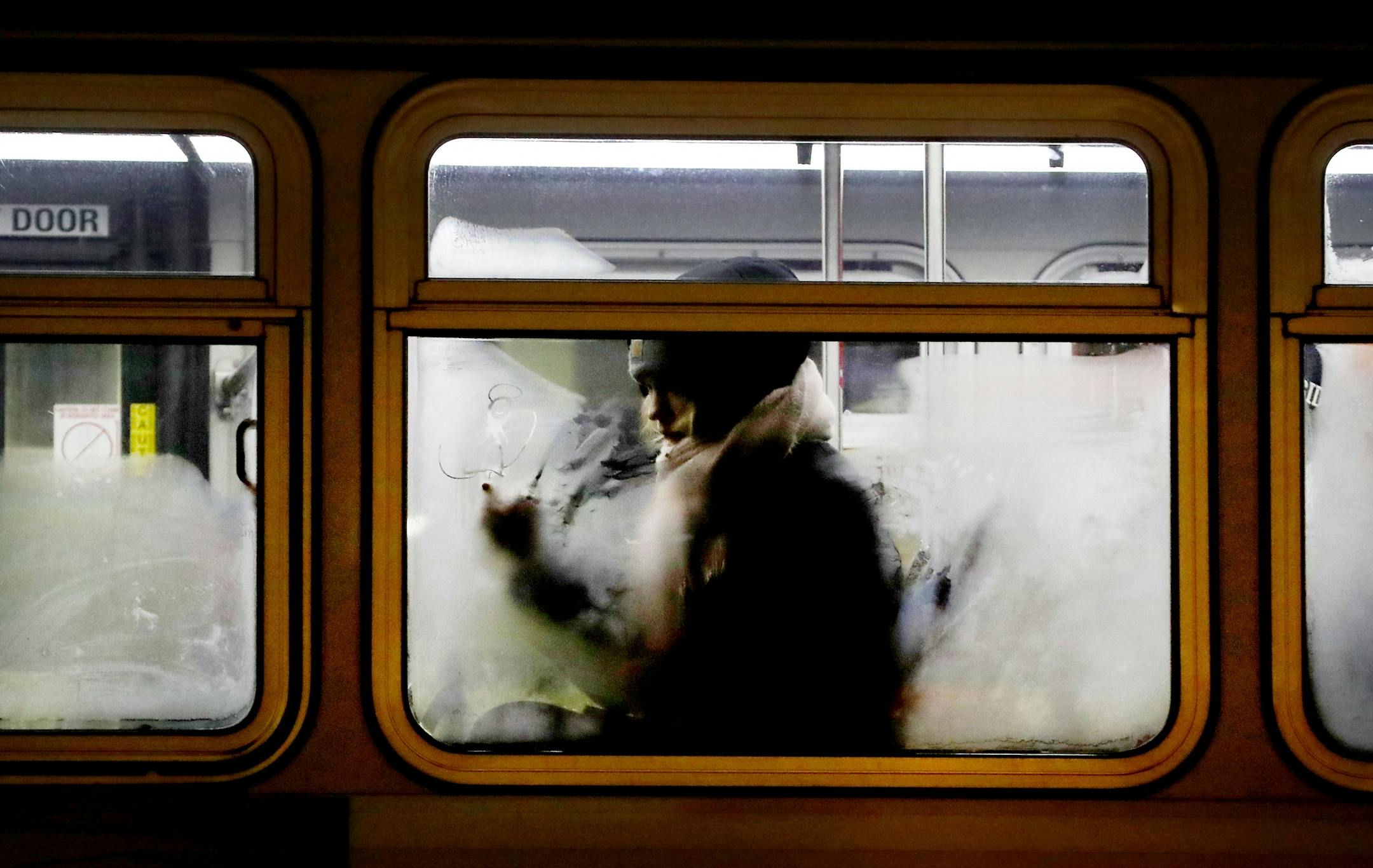 A commuter scratches an angel image into an icy window while sitting on a metro bus during frigid morning weather at the Chicago Lake Transit Center on Wednesday in Minneapolis.