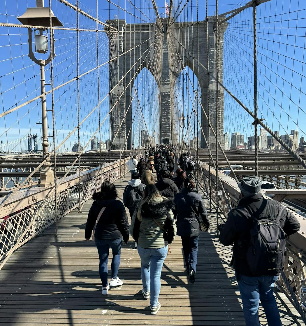 A busy pedestrian walkway on the Brooklyn Bridge in New York, on a sunny Sunday afternoon in March.