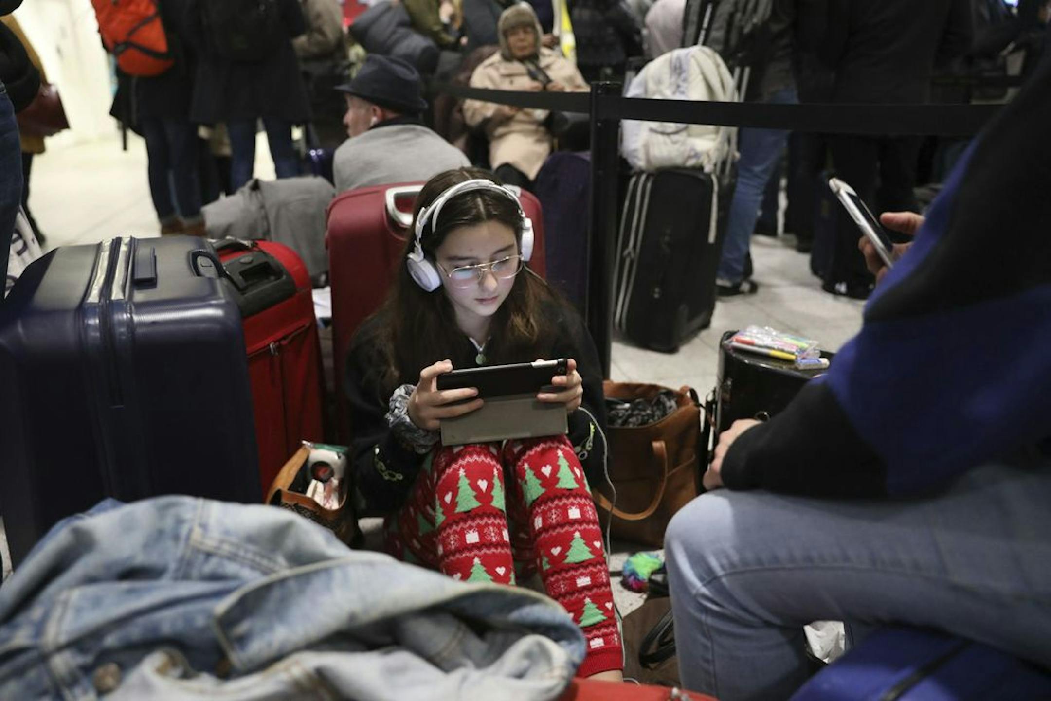 Passengers at Gatwick airport settle down to wait for their flights following the delays and cancellations brought on by drone sightings near the airfield, in London, Friday Dec. 21, 2018. New drone sightings Friday caused fresh chaos for holiday travelers at London's Gatwick Airport.