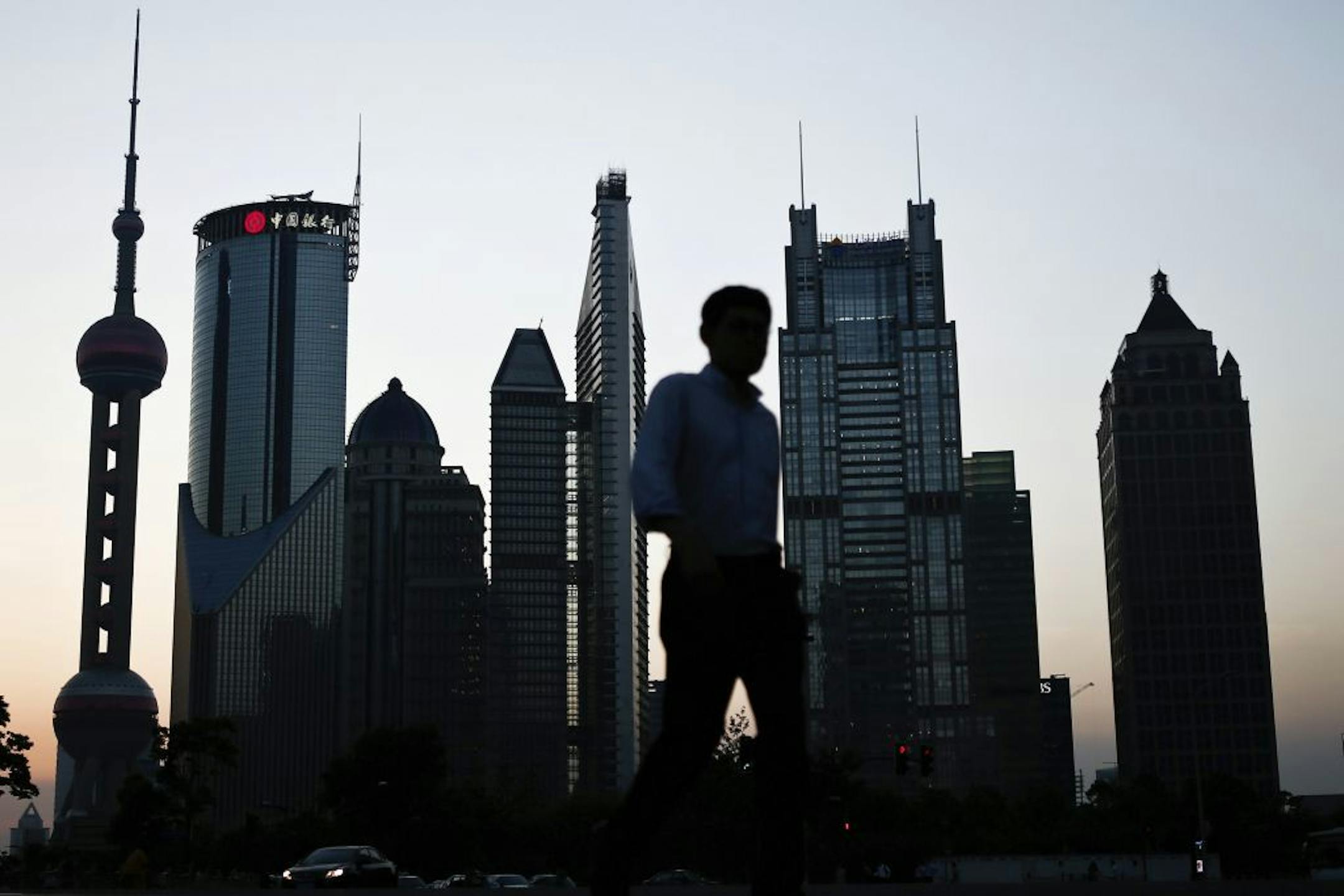In this photo taken July 10, 2013, a man walks past the downtown skyline of Shanghai, China. China's leaders face new pressure to stimulate a slowing economy after growth fell to its lowest since 1991, hurt by weak trade and efforts to cool a credit boom. The world's second-largest economy expanded 7.5 percent over a year earlier in the three months ending in June, down from the previous quarter's 7.7 percent, data showed Monday, July 15, 2013. (AP Photo) CHINA OUT