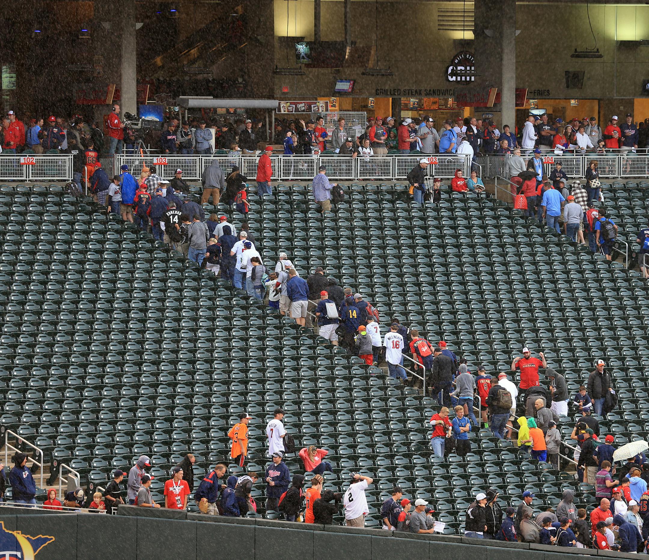 Rain force fans into cover for a brief moment as the player took batting practice. ] (KYNDELL HARKNESS/STAR TRIBUNE) kyndell.harkness@startribune.com During the All-Star Home run Derby at Target Field in Minneapolis, Min. Monday, July 14, 2014.