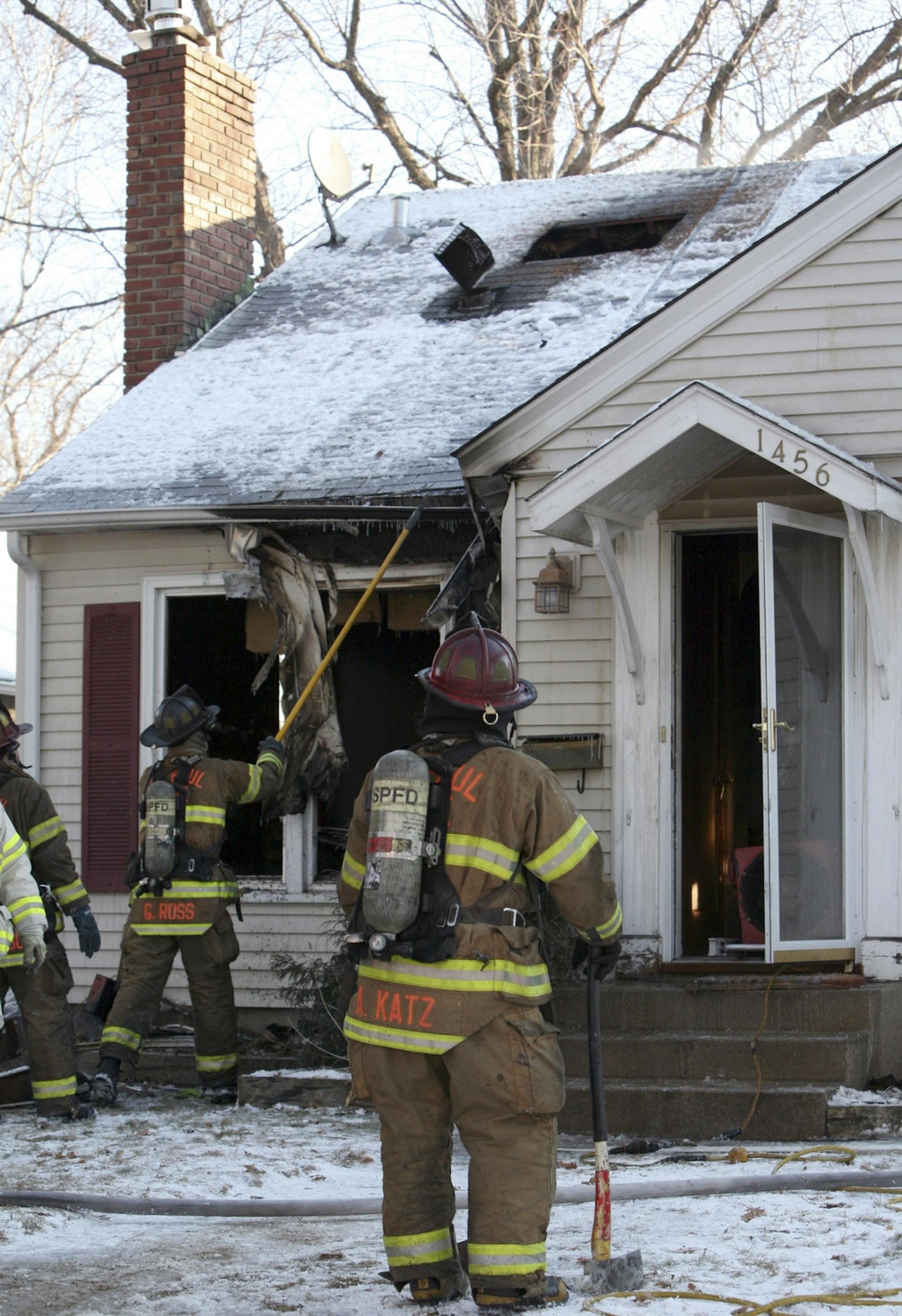 A St. Paul firefighter looks over the scene following a house fire at 1456 St. Albans St. in St. Paul on Monday, Jan. 2, 2012. A firefighter was burned after falling through the floor and into the basement while battling the fire.