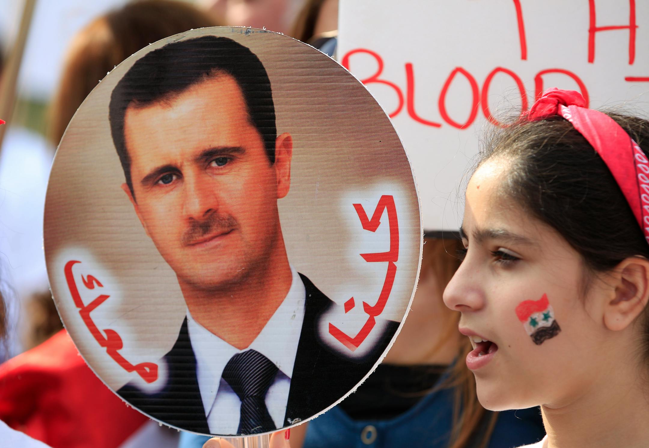 Syrian demonstrators carry an image of Syrian President Bashar Assad during a demonstration against US military action in Syria, Monday, Sept. 9, 2013, in front of the White House in Washington. On Tuesday, President Barack Obama will address the nation regarding Syria. (AP Photo/Jose Luis Magana)