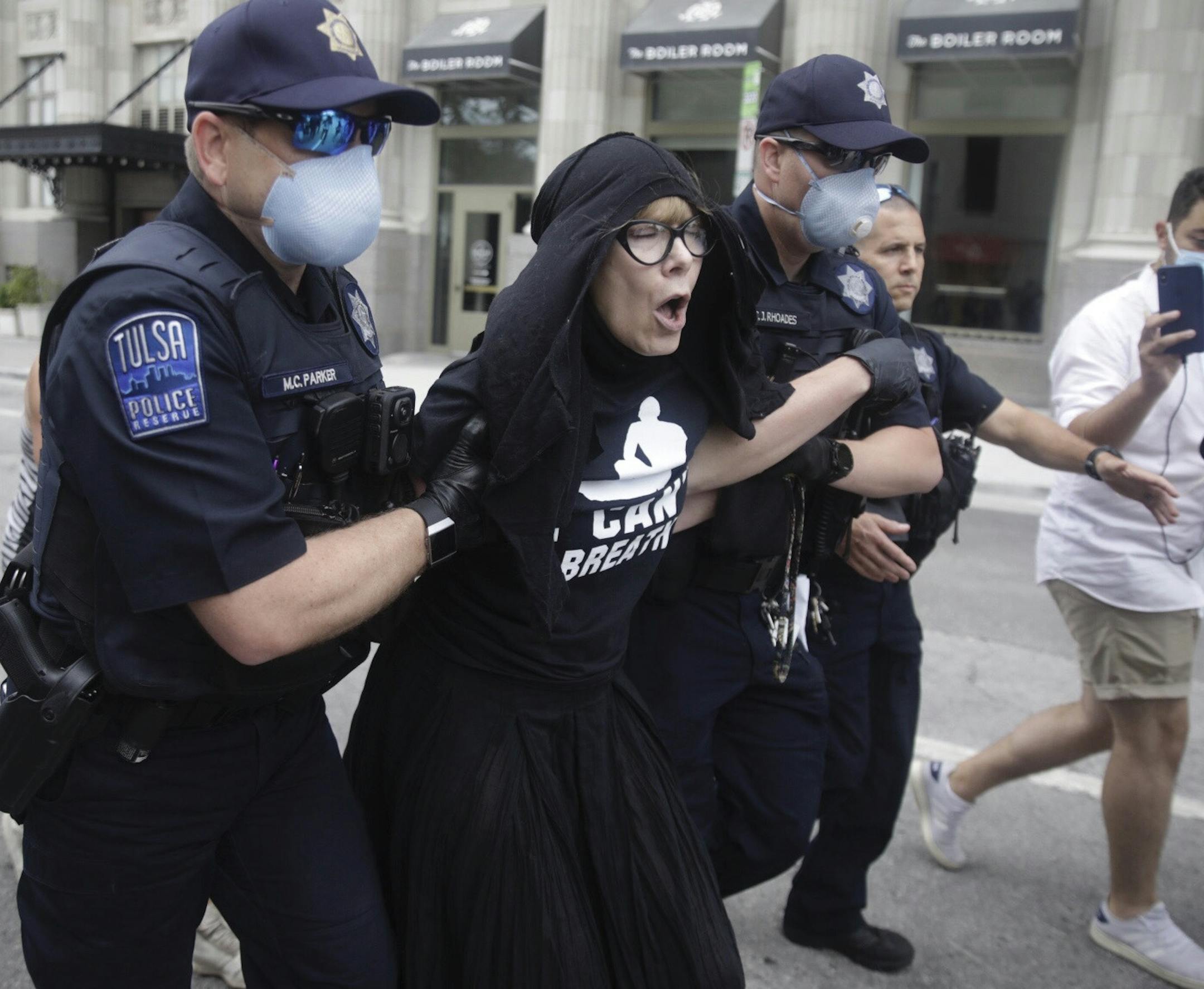 Tulsa Police officers arrest protester for trespassing after she entered the safety barricade of President Donald Trump's campaign rally Saturday June 20, 2020. (Mike Simons/Tulsa World via AP)