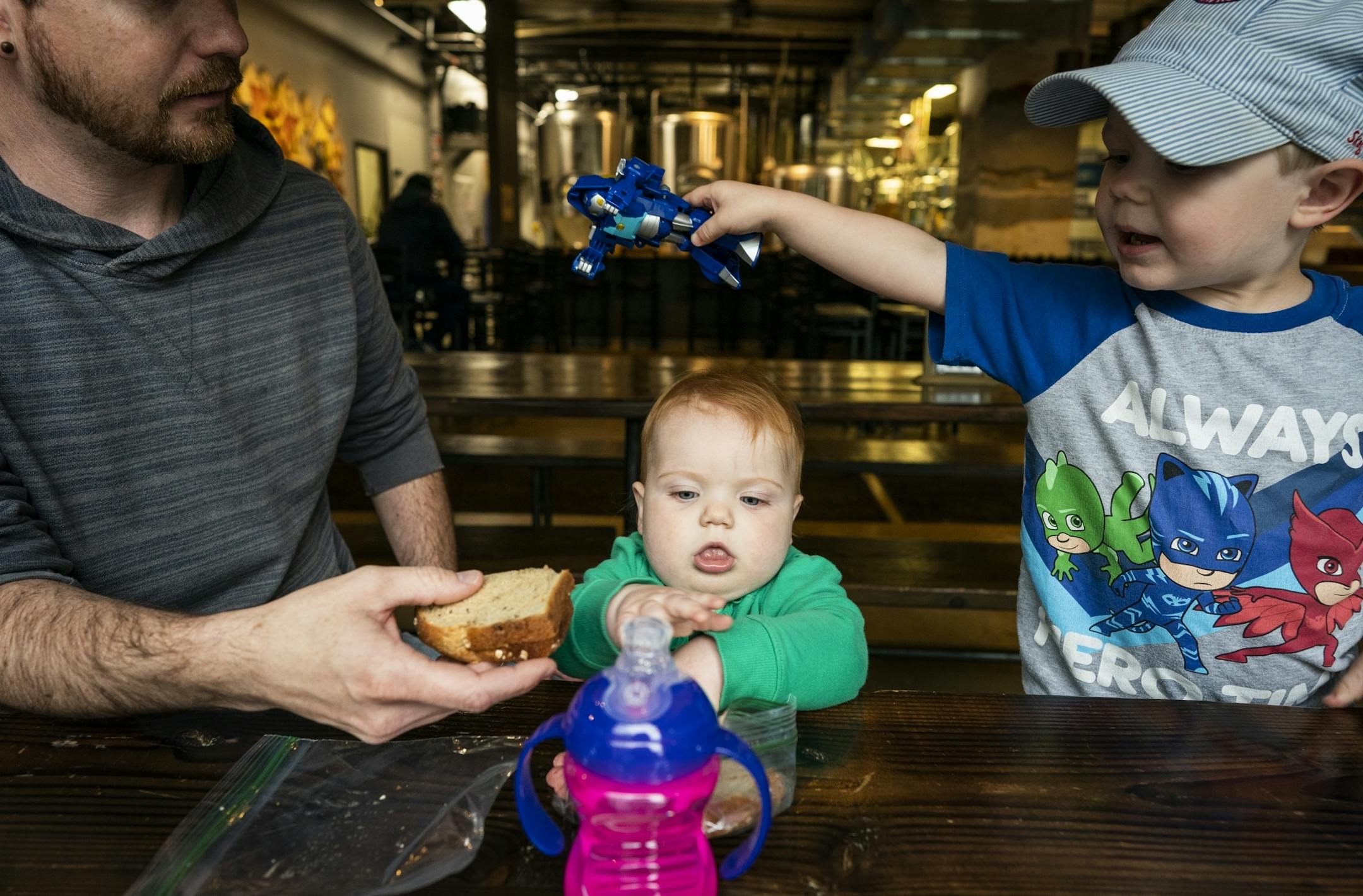 Nic Sabatke, left, with his daughter Mae, 1, and son Anders, 3, eat lunch during a Twin Cities Dads playgroup at Omni Brewing in Maple Grove.
