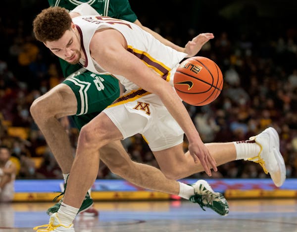 Gophers forward Jamison Battle (10) fought for a loose ball in the team’s last game against Wisconsin Green Bay.