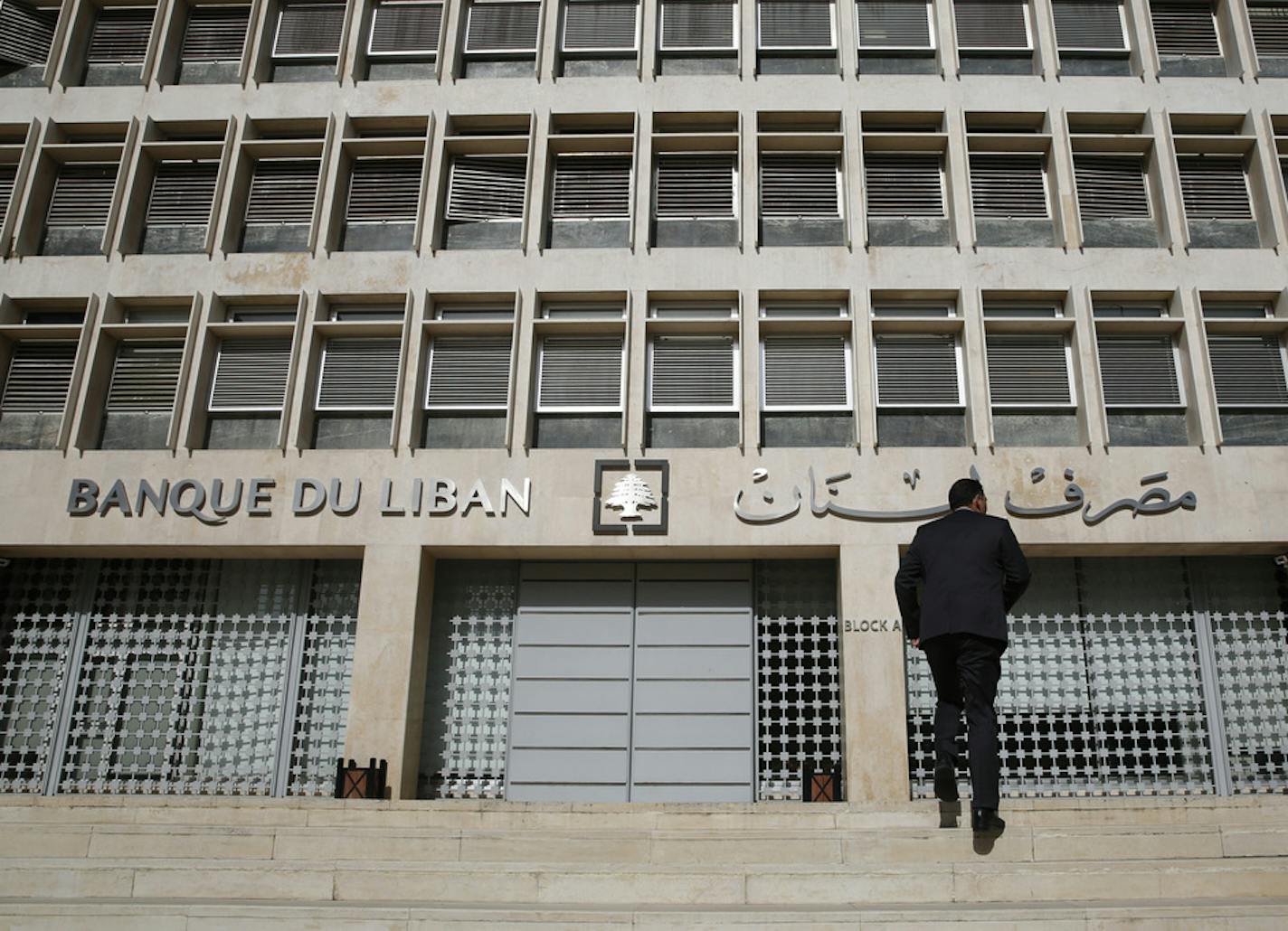 FILE - This Jan. 22, 2019, file photo, a man heads to the Lebanese central bank in Beirut, Lebanon. Lebanon's central bank has issued guarantees to secure U.S. dollars for local banks at the fixed official rate that would cover imports of fuel, wheat and medicine. The central bank's move on Tuesday, Oct. 1, 2019 aims to ease the demand for dollars at a time when many Lebanese are rushing to exchange shops to convert their local currency into dollars. (AP Photo/Hussein Malla, File)