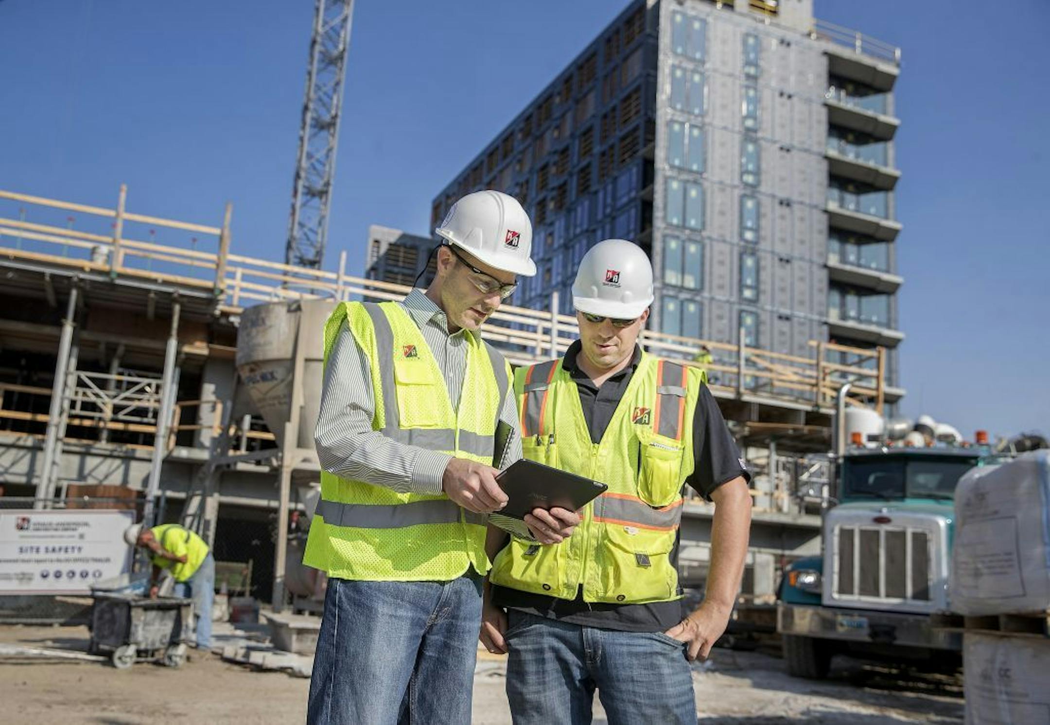 Kraus-Anderson is building the Iron Clad hotel and apartment tower for a client; the company's new Building Science Group, which is headed by Jon Porter, is advising on the project. Here Porter, left, consulted with a co-worker near the building being built, Friday, August 17, 2018 in Minneapolis, MN.