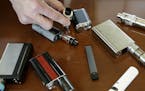 FILE - In this Tuesday, April 10, 2018, file photo, a high school principal displays vaping devices that were confiscated from students in such places