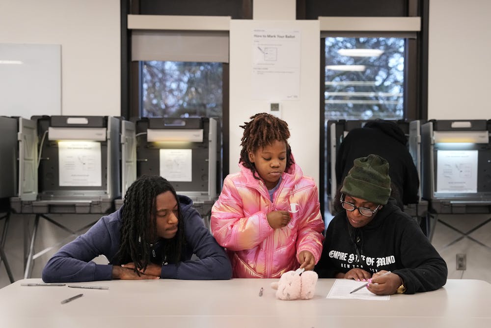 Christiana Taylor, 11, sits with her brother Quintin Melton and mother Chantal as she looks over her ballot while voting on Election Day Tuesday, Nov. 5, 2024 at the North Regional Library in north Minneapolis.  ] ANTHONY SOUFFLE • anthony.souffle@startribune.com