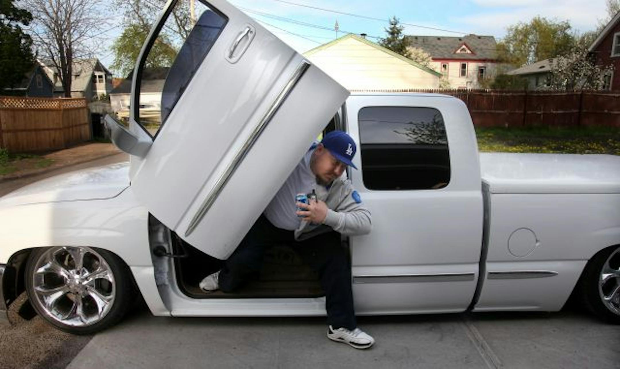 Antonio Garcia of Burnsville makes a grand exit from his '99 GMC Sierra lowrider pickup with tilt-up doors.
