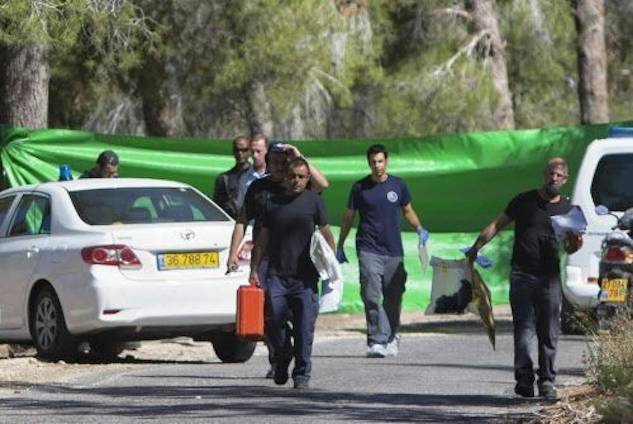 Israeli forensic police officers carry evidence bags in a forest in Jerusalem, Wednesday, July 2, 2014, where the body of a kidnapped Arab teen reportedly was found.