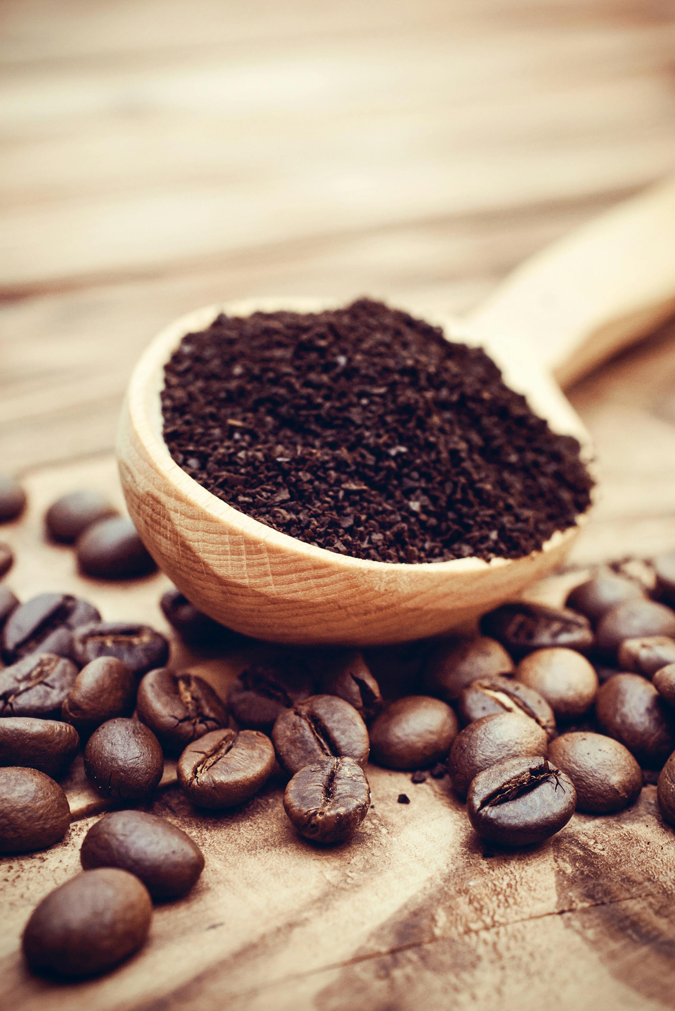 istock Wooden spoon with ground coffee and coffee beans on the table. Close up.