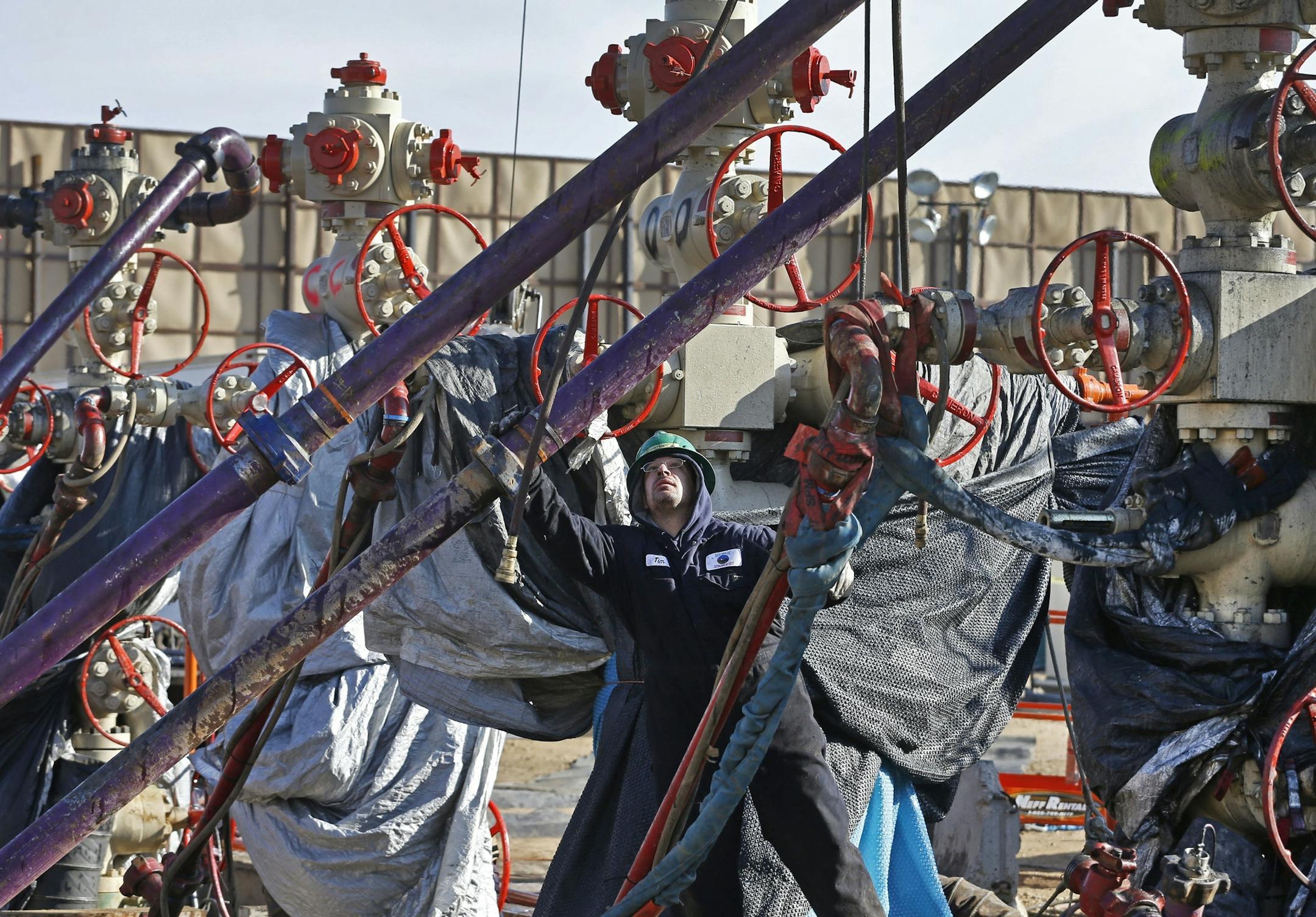 FILE - In this March 25, 2014 file photo, a worker adjusts pipes during a hydraulic fracturing operation at a well pad near Mead, Colorado. The Trump administration is moving to roll back Obama-era rules intended to reduce leaks of climate-changing methane from oil and gas facilities. The Environmental Protection Agency formally released a proposed substitute rule Tuesday. The EPA acknowledges the rollback would lead to more methane leaking into the atmosphere. The agency says relaxing oversight