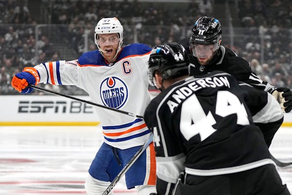 Oilers center Connor McDavid, left, battles with  Kings center Anze Kopitar, right, and defenseman Mikey Anderson during the third period Sunday in Lo