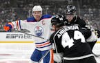 Oilers center Connor McDavid, left, battles with  Kings center Anze Kopitar, right, and defenseman Mikey Anderson during the third period Sunday in Lo