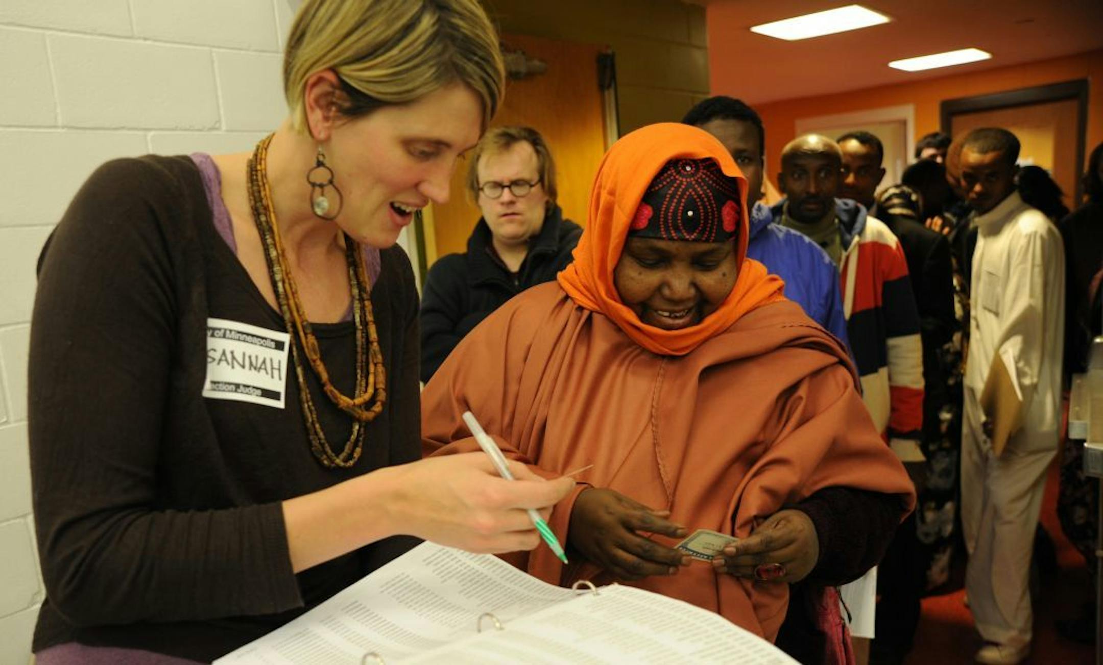 Susannah Dodge, an election judge, helped Hawo Mumin through a long voting line at the Brian Coyle Center in Minneapolis.. She was applying for voter registration and it was her first time voting.