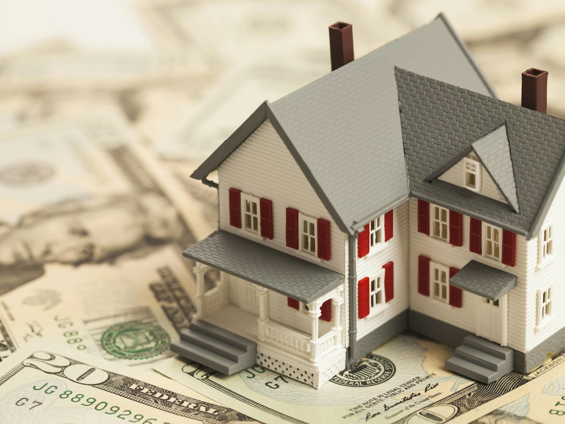 Single family house on pile of money. Concept of real estate.