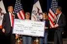 FILE - In this Jan. 31, 2016 file photo, Donald Trump, left, stages a check presentation with an enlarged copy of a $100,000 contribution from the Don