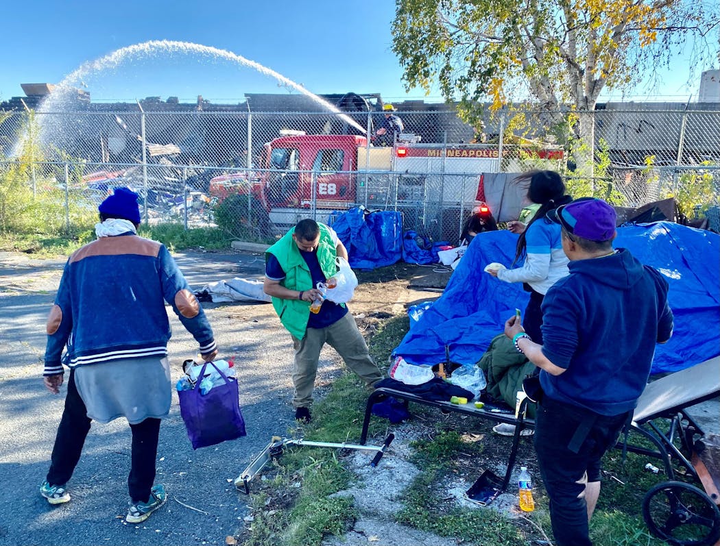 Residents of a homeless encampment policed their area as a firefighter soaked down the back of the vacant Kmart, which caught fire early Friday.