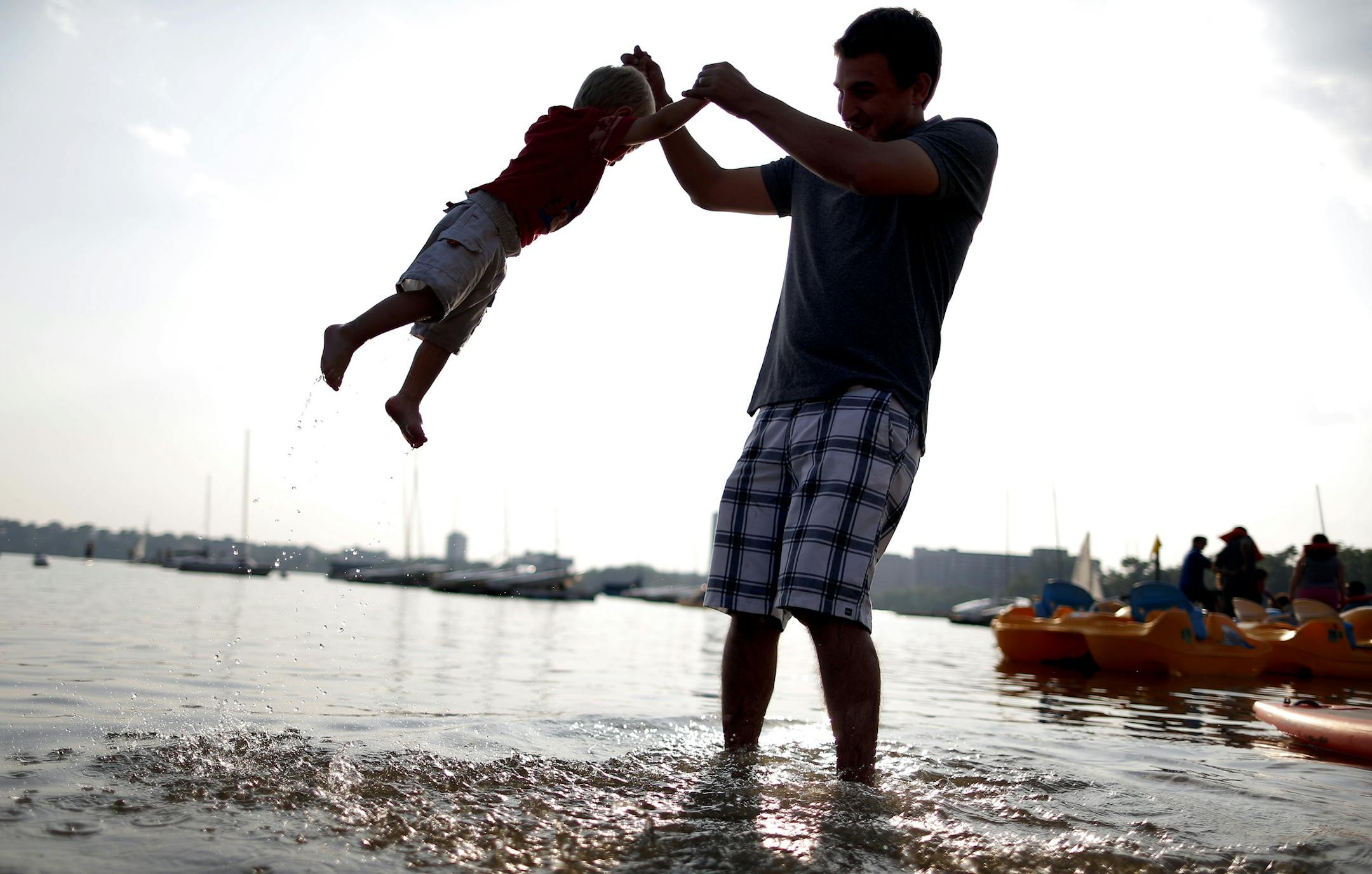 Dan Johnson, 30, of Maple Grove swung his son Noah, 2, while his mother Candace, waited in line at Wheel Fun Rentals on Lake Calhoun in Minneapolis on Wednesday evening. ] CARLOS GONZALEZ cgonzalez@startribune.com July 10, 2013, Minneapolis, Minn., Is a land bridge over Lake Street the fix for summer congestion at the northeast corner of Lake Calhoun, where users of the Chain of Lakes, the state's busiest park, intersect with the busiest Hennepin County's county highway? That's one idea being ad