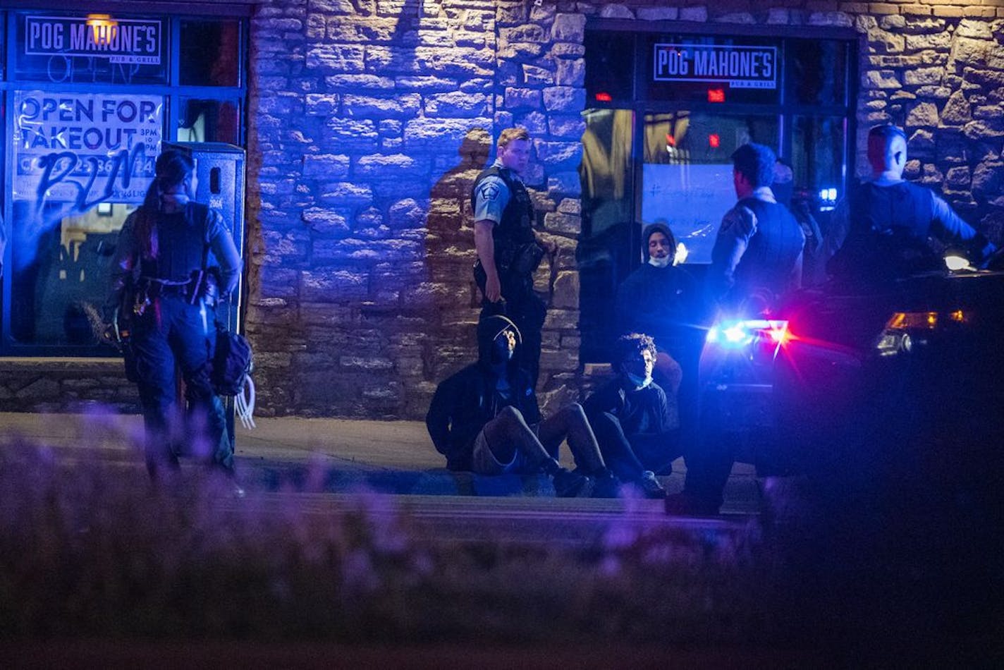 People in a vehicle are detained on Washington Avenue by Minneapolis Police in downtown Minneapolis after curfew.