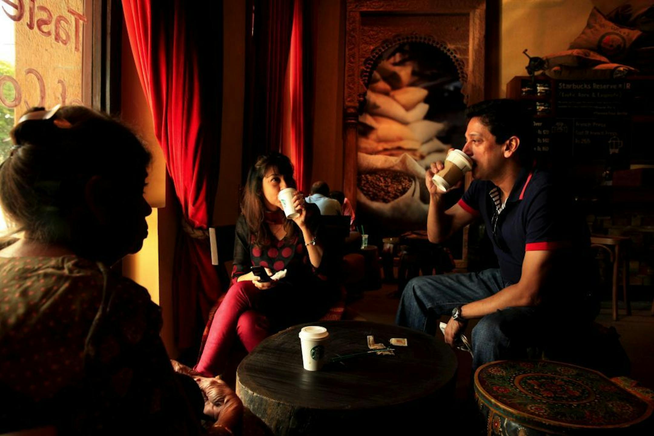 Jyoti Sujan, left, her daughter Meena Sujan and son Harsh Sujan talk over drinks inside the Starbucks' flagship store at Horniman Circle in south Mumbai. The two-level store is decorated with ornate Indian imagery.