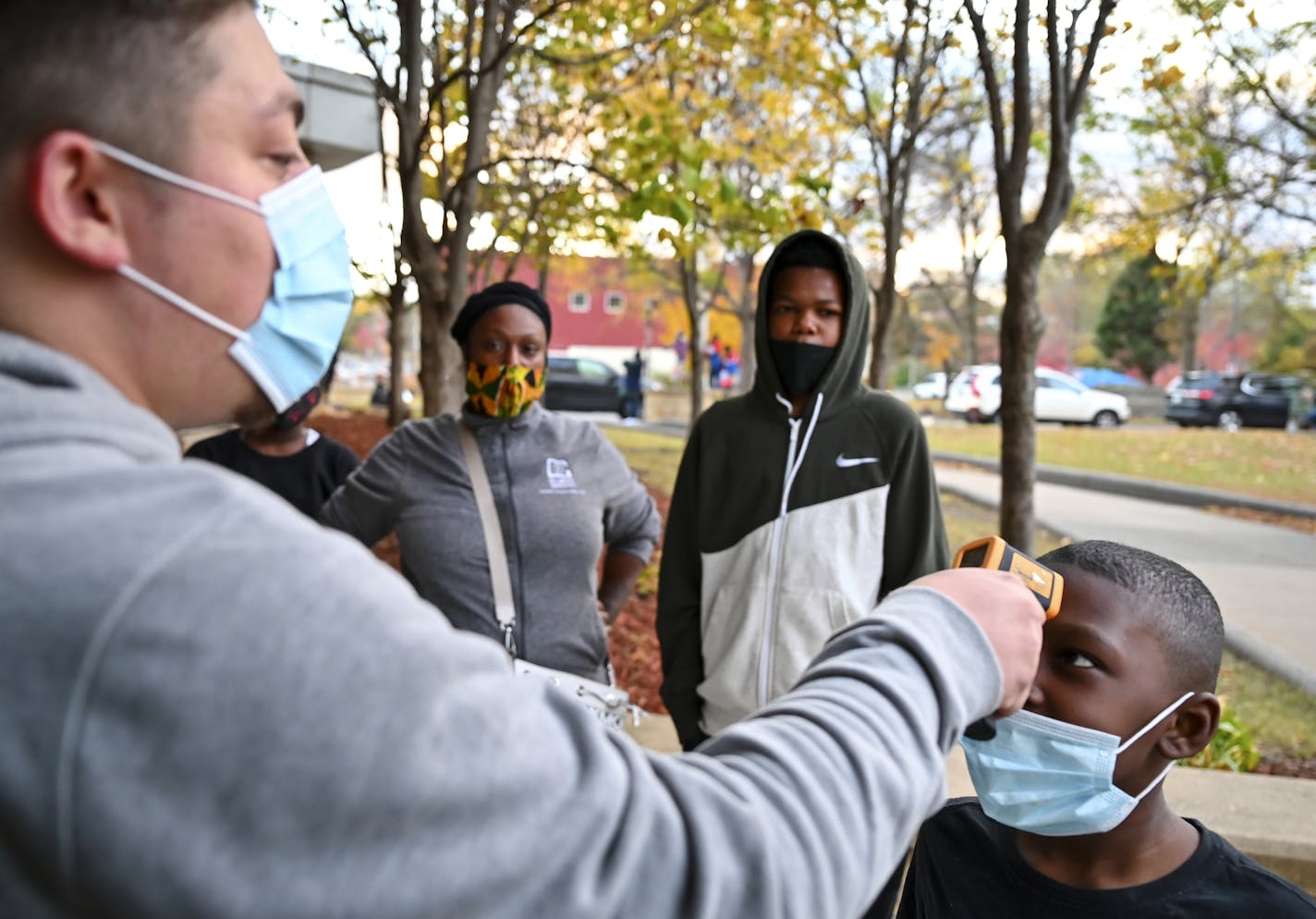 West Side Boosters President Carlo Franco checked the temperature of Rico Williams, 8 before letting him inside El Rio Vista Recreation center Wednesday night for a basketball tryout. ] AARON LAVINSKY • aaron.lavinsky@startribune.com A story looking at how COVID-19 continues to impact youth sports. Between volunteer coaches having to add COVID protocols to their duties in some cities to others moving away from traditional soccer and football games to more of a skills camp setting, the virus didn