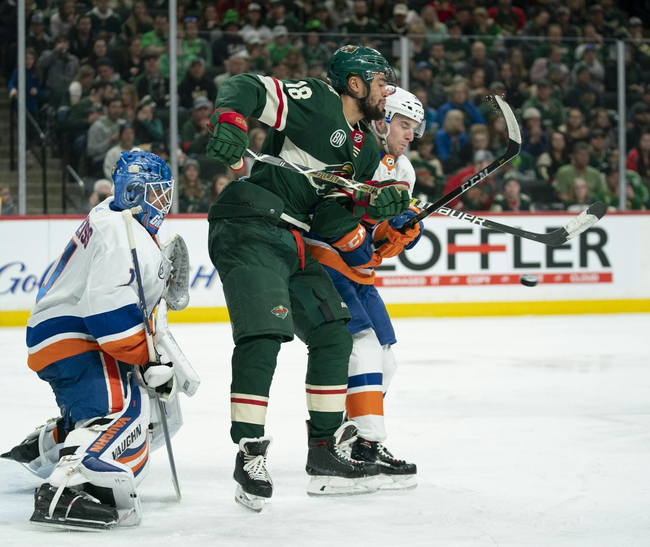 Minnesota Wild left wing Jordan Greenway (18) tried to deflect an incoming shot while defended by New York Islanders defenseman Devon Toews (25) in front of Islanders goaltender Thomas Greiss in the second period.