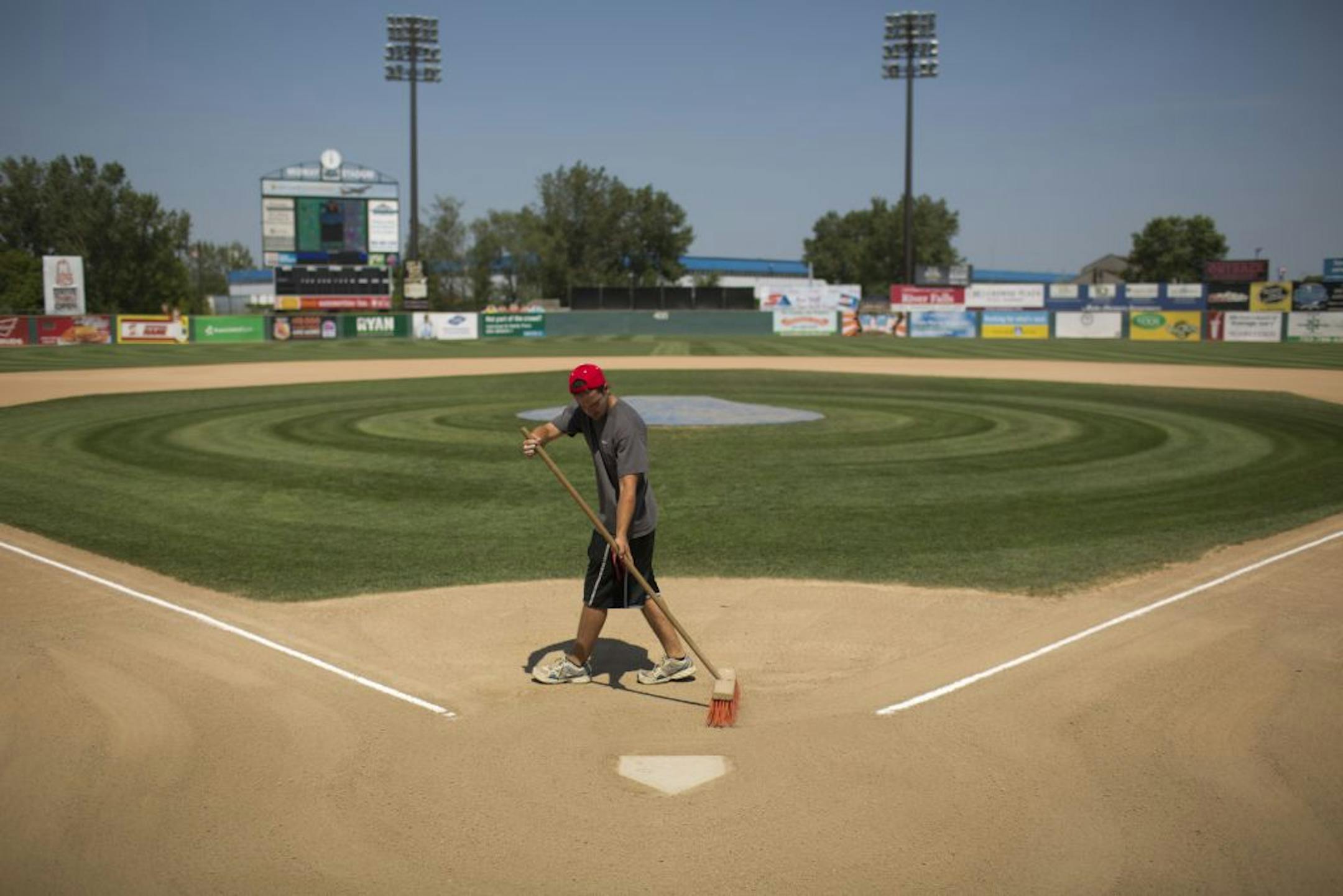 Luke Wittrock, a groundskeeper at Midway Stadium, groomed the surface around home plate on Monday afternoon, hours before game time.