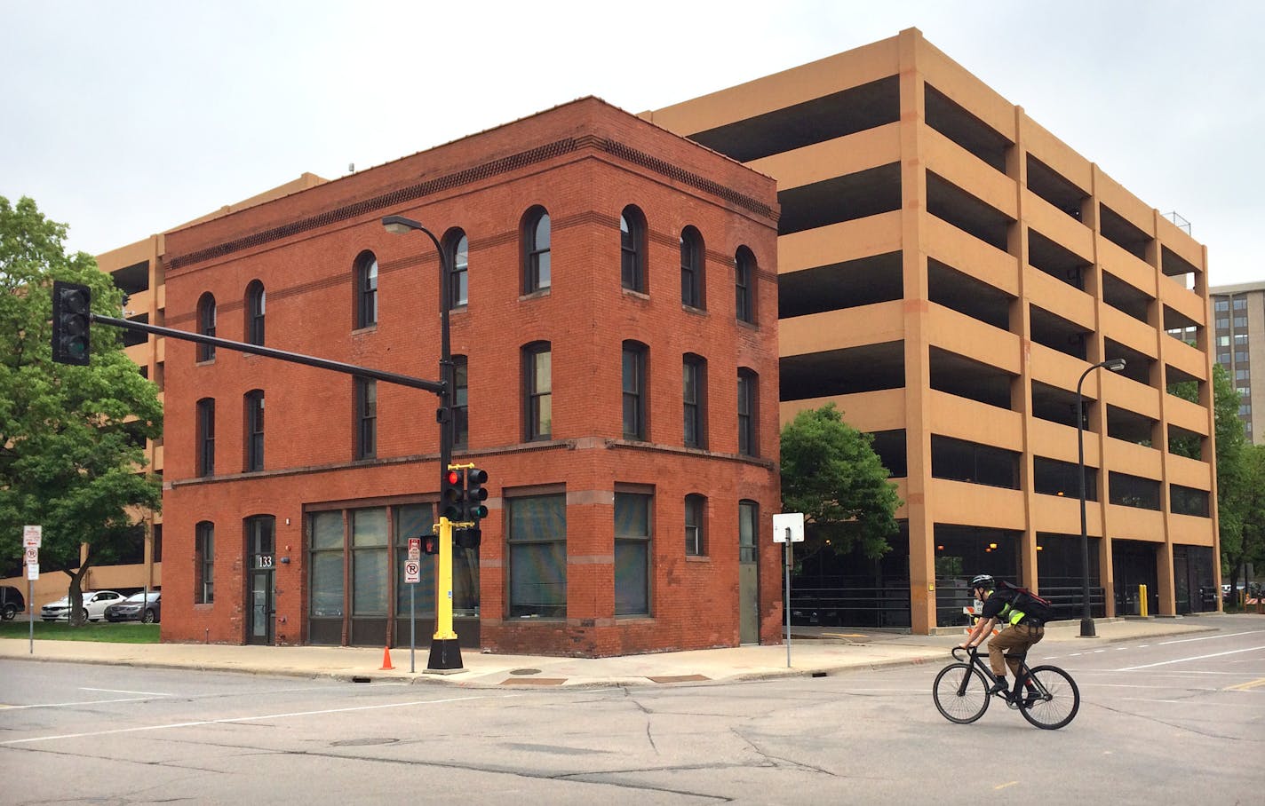 A row of townhouses with individual entrances and garages will be built along First Avenue on the back of the parking garage and adjacent to this smaller brick building. A six-story apartment building facing Hennepin Avenue will replace a parking lot and trees in front of the parking garage. ] Photo: Jim Buchta - Star Tribune Minneapoils, MN 5/20/15