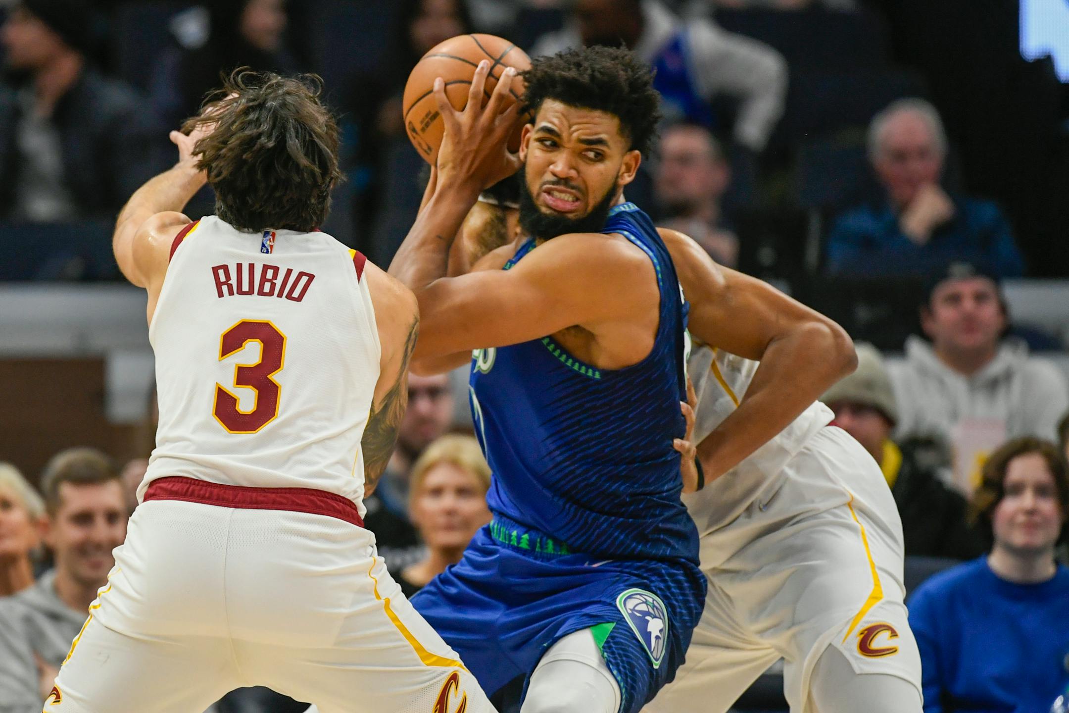 Minnesota Timberwolves center Karl-Anthony Towns, center, looks to pass the ball while covered by Cleveland Cavaliers guard Ricky Rubio (3) and center Jarrett Allen in the second half of an NBA basketball game Friday, Dec. 10, 2021, in Minneapolis. (AP Photo/Craig Lassig)
