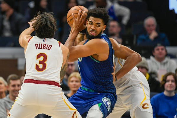 Minnesota Timberwolves center Karl-Anthony Towns, center, looks to pass the ball while covered by Cleveland Cavaliers guard Ricky Rubio (3) and center
