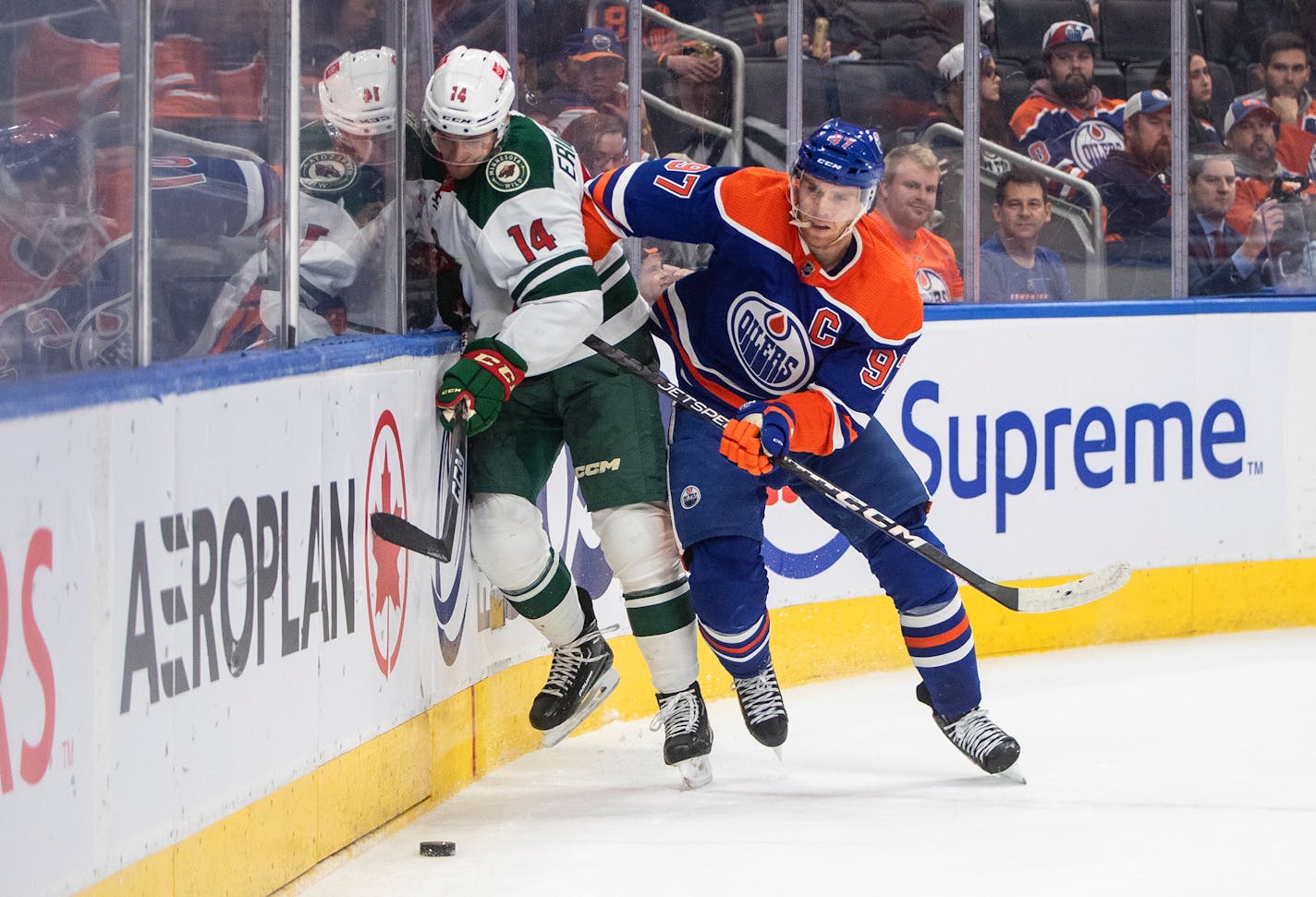 Minnesota Wild's Joel Eriksson Ek (14) is checked by Edmonton Oilers' Connor McDavid (97) during first-period NHL hockey game action in Edmonton, Alberta, Friday, Dec. 9, 2022. (Jason Franson/The Canadian Press via AP)