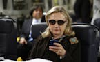 FILE - In this Oct. 18, 2011, file photo, then-Secretary of State Hillary Rodham Clinton checks her Blackberry from a desk inside a C-17 military plan