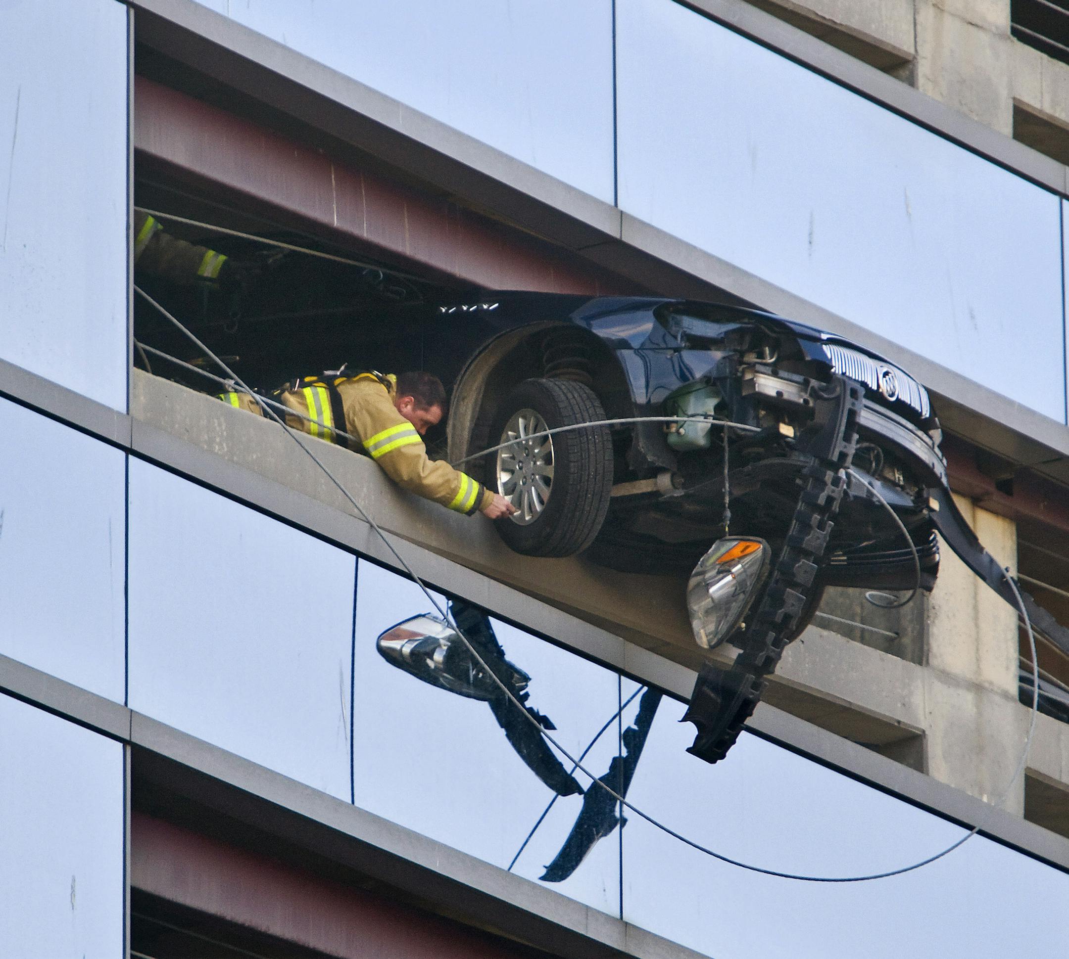A firefighter deflated a tire to help in the removal of a car that went through a retaining barrier on the eighth floor of the Damon West parking ramp on the edge of the Mayo Clinic campus in Rochester on Friday morning. The two occupants escaped unharmed.