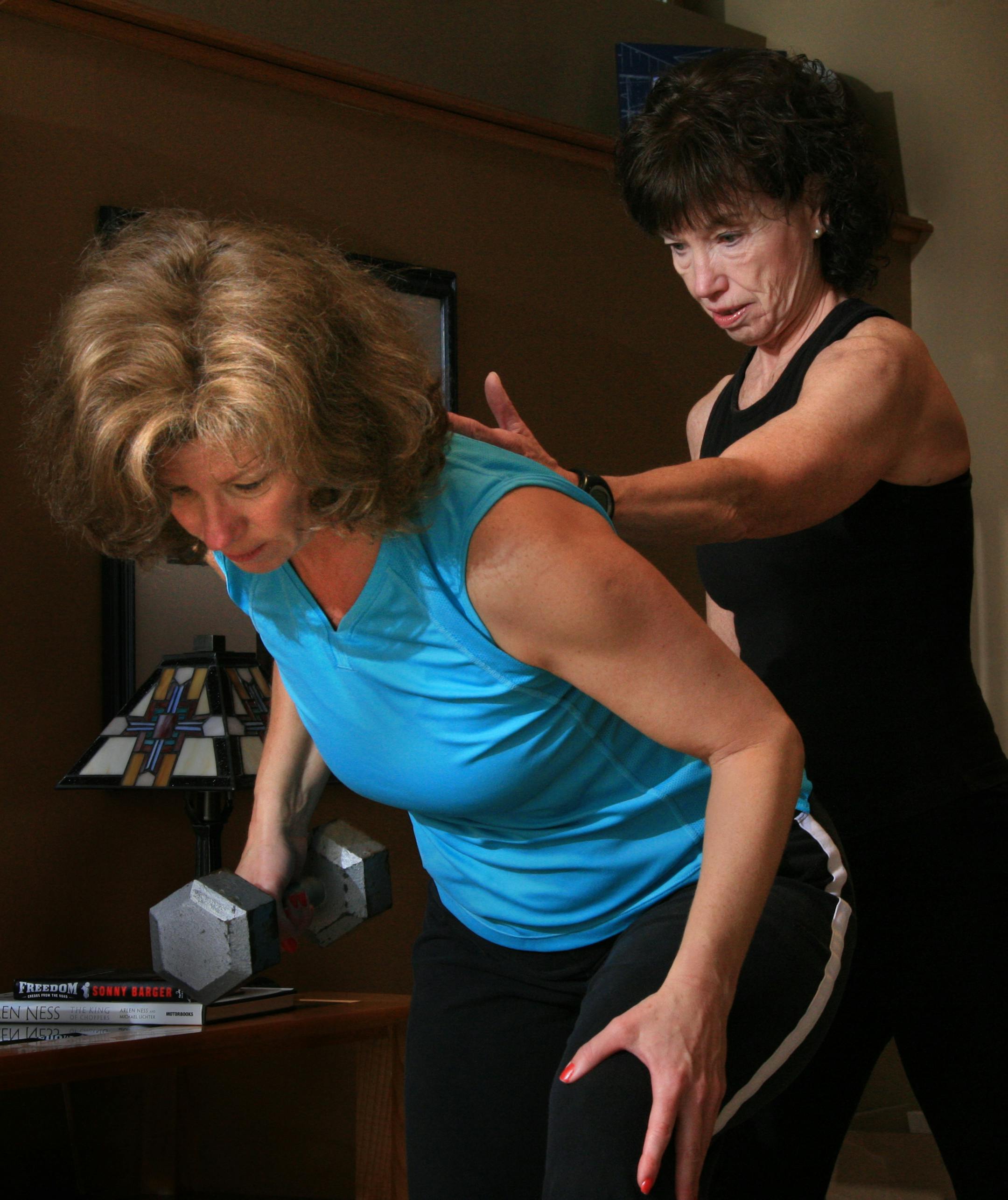 Jackie Goodwin, a personal trainer, helps Jane Schmidt with her form during a home workout. Goodwin comes to Schmidt's house one a week for personal training, they have been working together for the last year. Goodwin also leads aerobic classes that Schmidt attends.