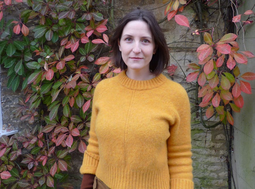 photo of author Nell Stevens in front of a vine-covered wall