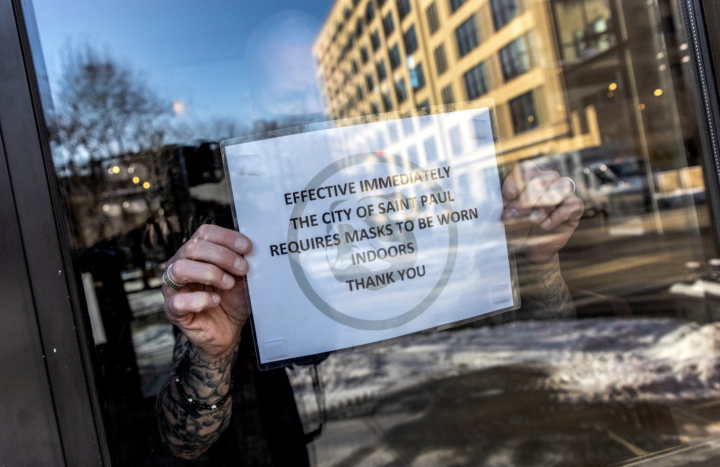 Tony Moline the general manager of Bulldog Lowertown places a mask sign on the front door Thursday, Jan. 5, 2022 at The Bulldog in St. Paul, Minn. ] CARLOS GONZALEZ • cgonzalez@startribune.com