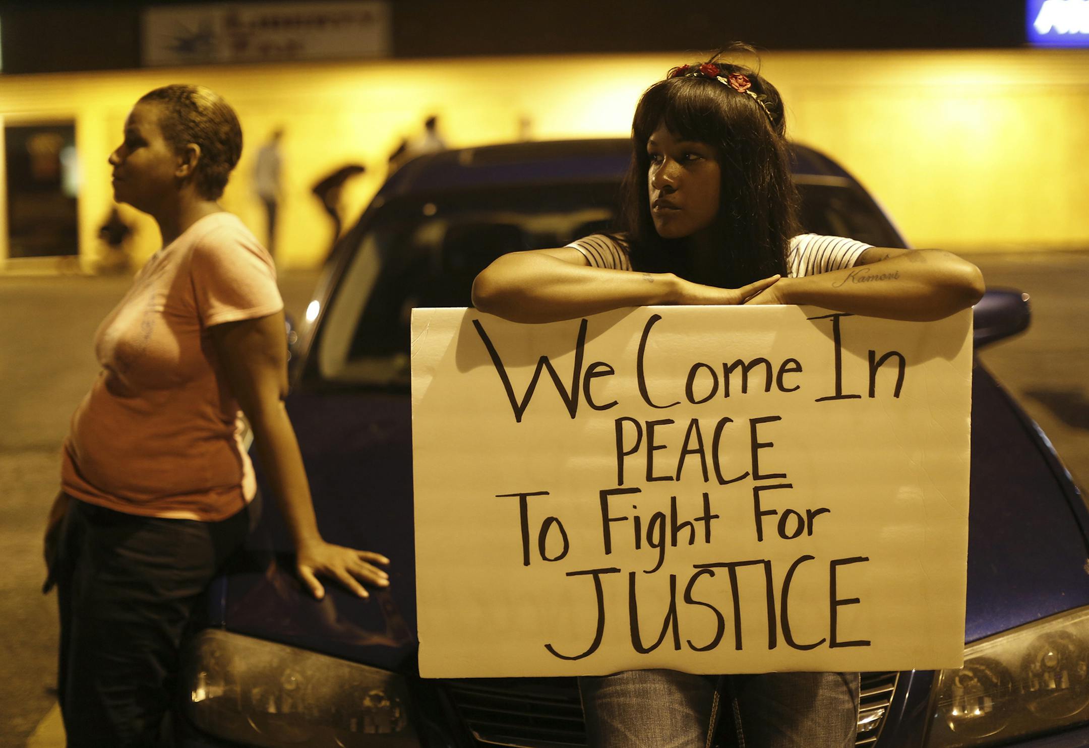A protester with a sign during demonstrations in Ferguson, Mo., the night of Aug. 19, 2014. After peaceful demonstration concluded just before midnight, a fresh wave of confrontation briefly shook Ferguson Tuesday night, showing way to more tension hours before a county grand jury was to start considering evidence in the shooting death of an unarmed black teenager, Michael Brown, by a white police officer on Aug. 9. (Whitney Curtis/The New York Times) ORG XMIT: MIN2014082011525933
