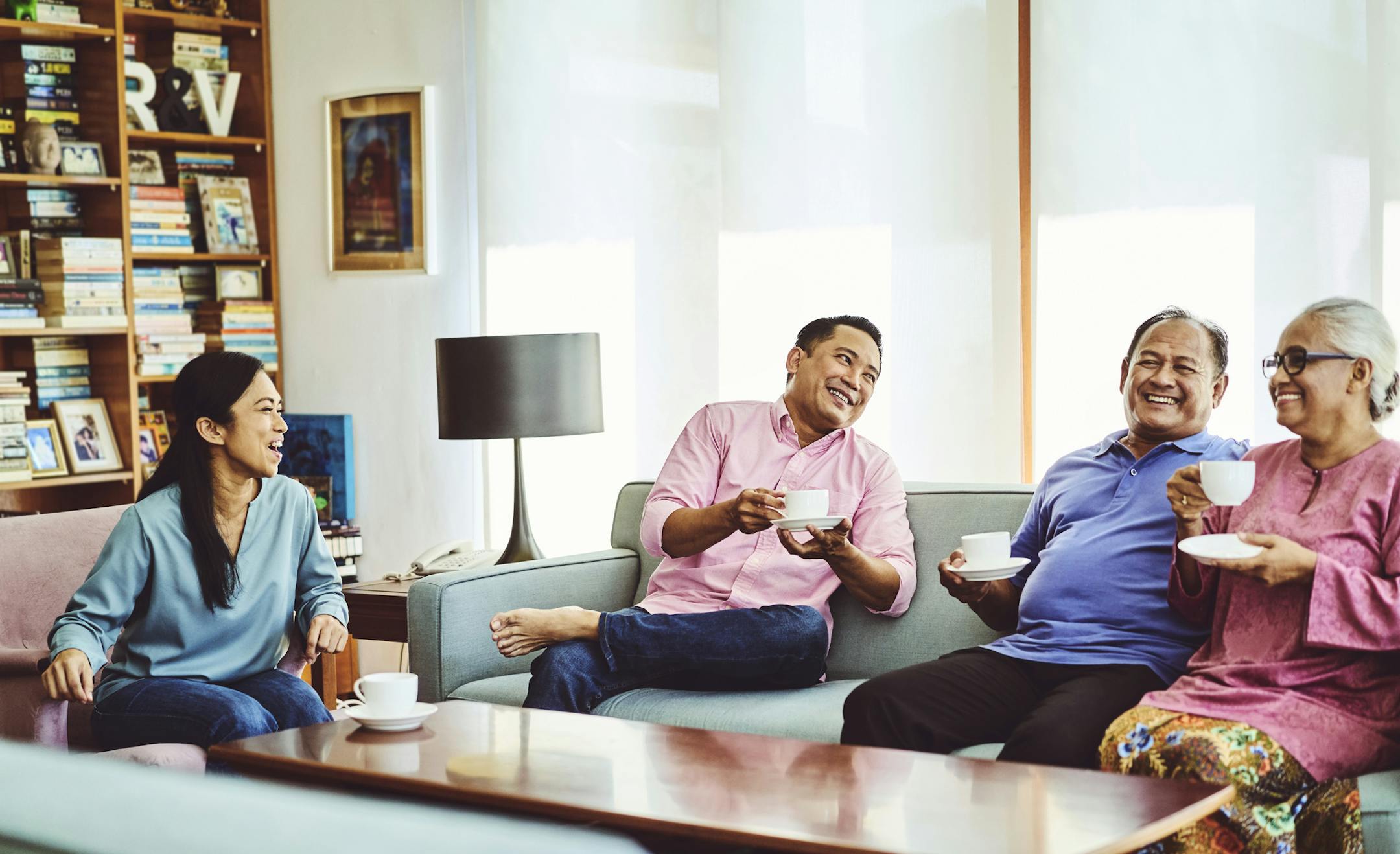 Happy family drinking coffee while sitting in living room. Males and females are spending leisure time at home. They are in casuals. ORG XMIT: 775109147