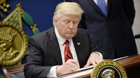 United States President Donald Trump signs Executive Orders in the Hall of Heroes at the Department of Defense in Virginia, January 27, 2017. Credit: 