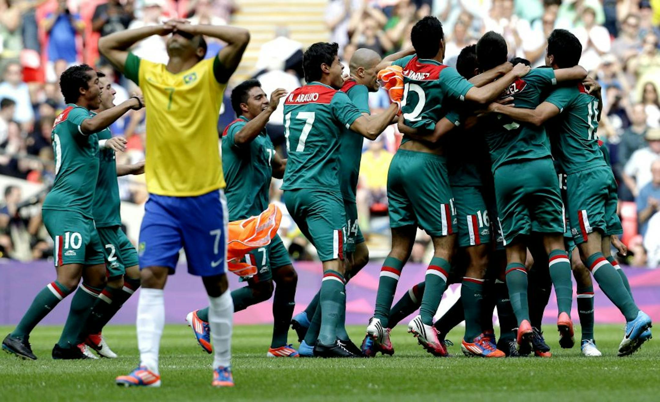 Brazil's Lucas walks away as Mexico players celebrate winning the gold medal in the men's soccer final at the 2012 Summer Olympics, Saturday, Aug. 11, 2012, in London.