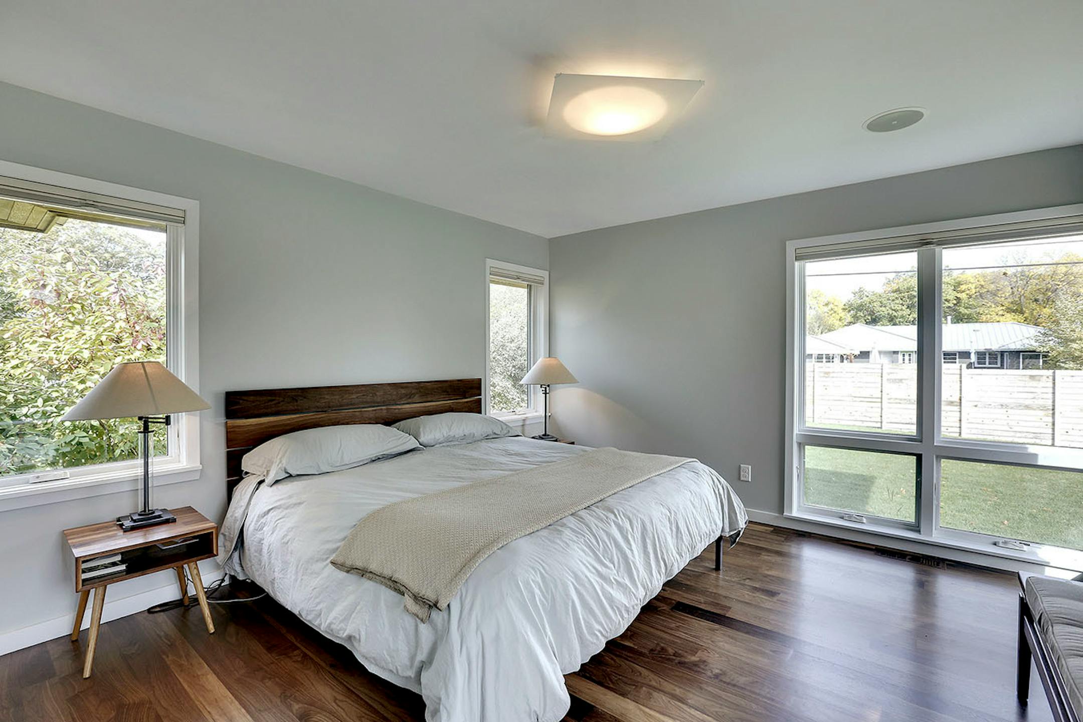 The second addition holds the owner's suite with a walk-in closet and bathroom. The custom walnut bed and nightstand match the walnut floors.