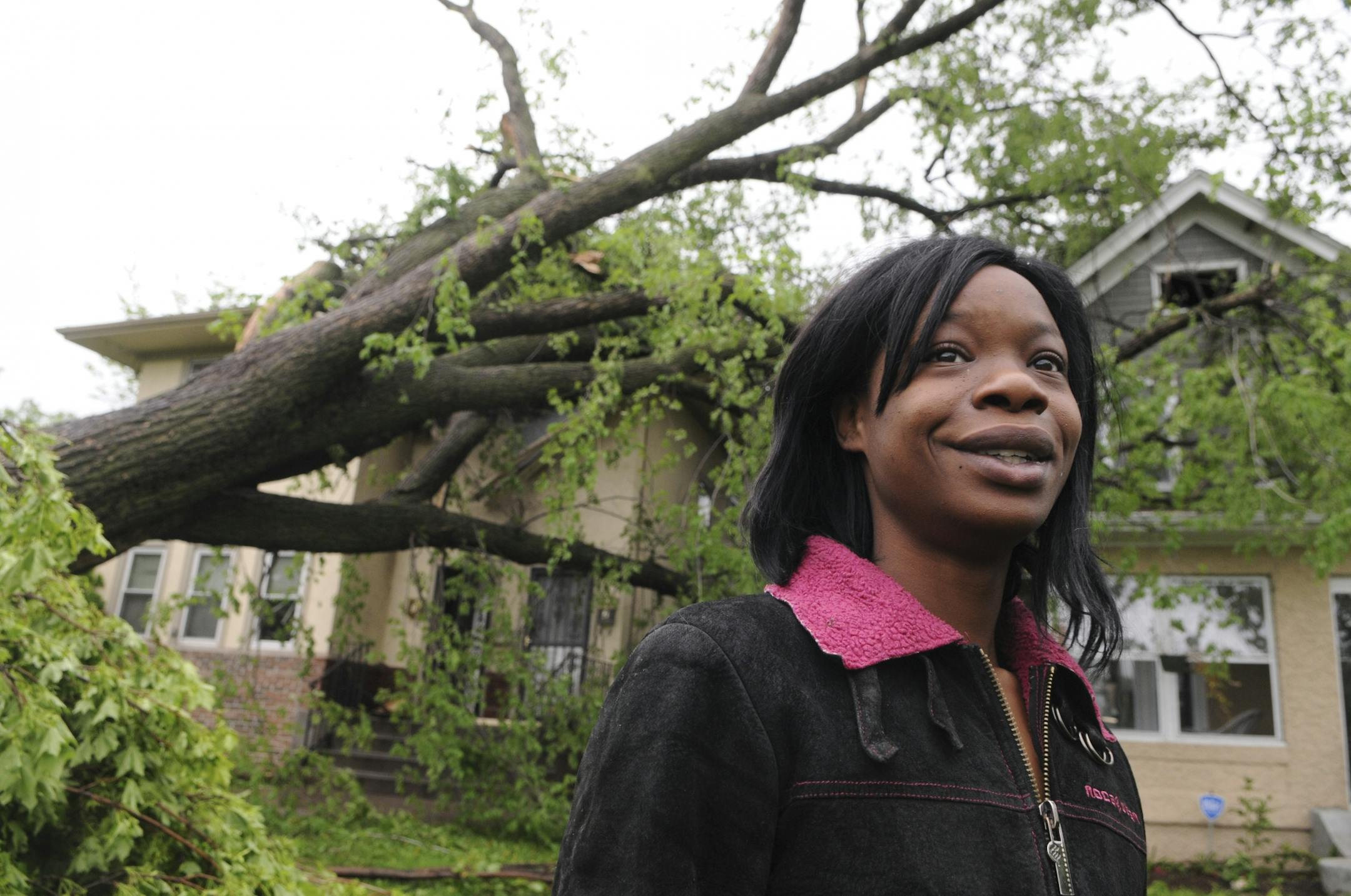 Carrie Pigue was out Monday to survey storm damage in her north Minneapolis neighborhood. A large tree fell on her house, pictured behind her.