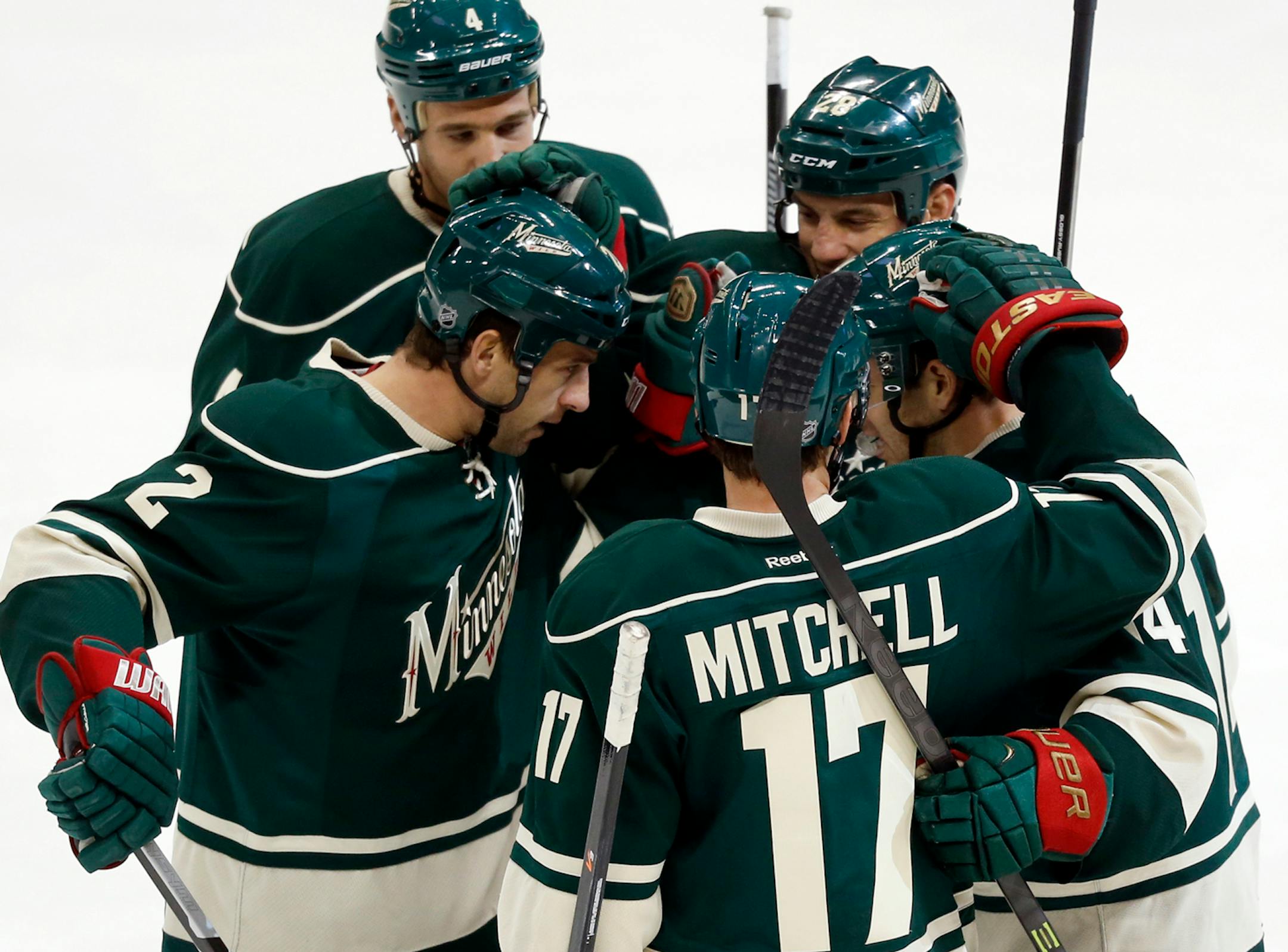 The Minnesota Wild's Justin Fontaine (14) is greeted by teammates Clayton Stoner (4), upper left, counter clockwise, Keith Ballard (2), Torrey Mitchell (17) and Zenon Konopka (28) after Fontaine's first period goal.