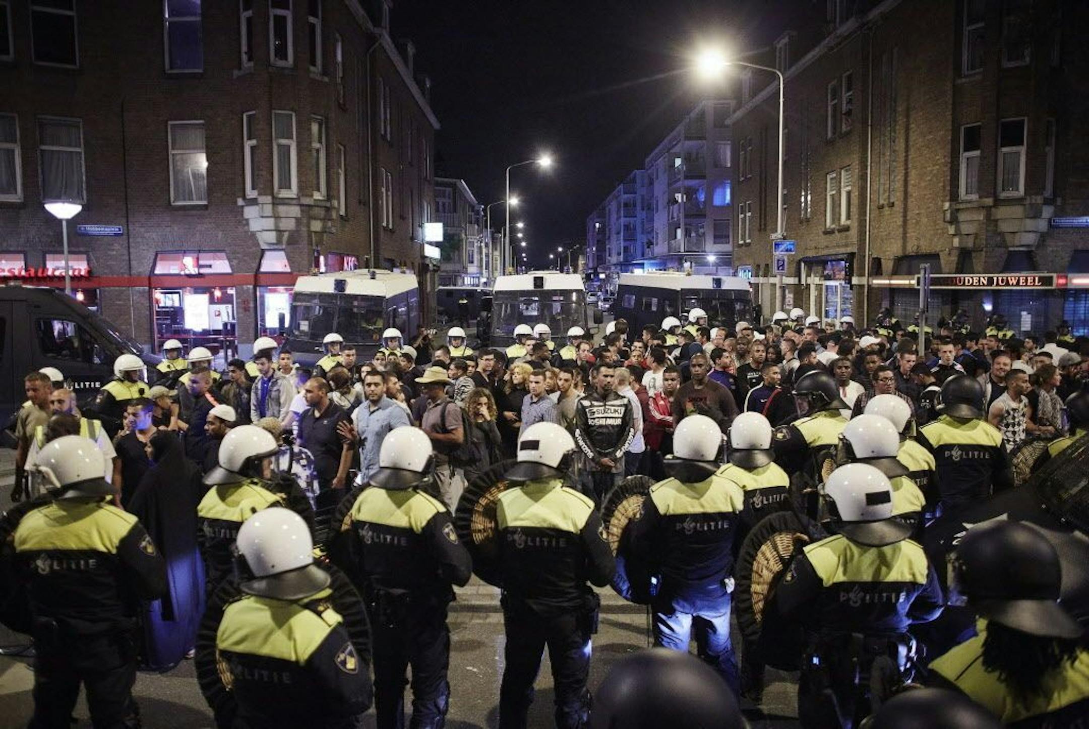 Dutch riot police surround detained suspects at Schilderswijk district in The Hague, Netherlands, in the early hours of Friday, July 3, 2015. Dutch police have detained some 200 people for ignoring a ban on public assembly imposed in a neighborhood hit by days of late-night rioting following the death in police custody of a man arrested at a music festival.