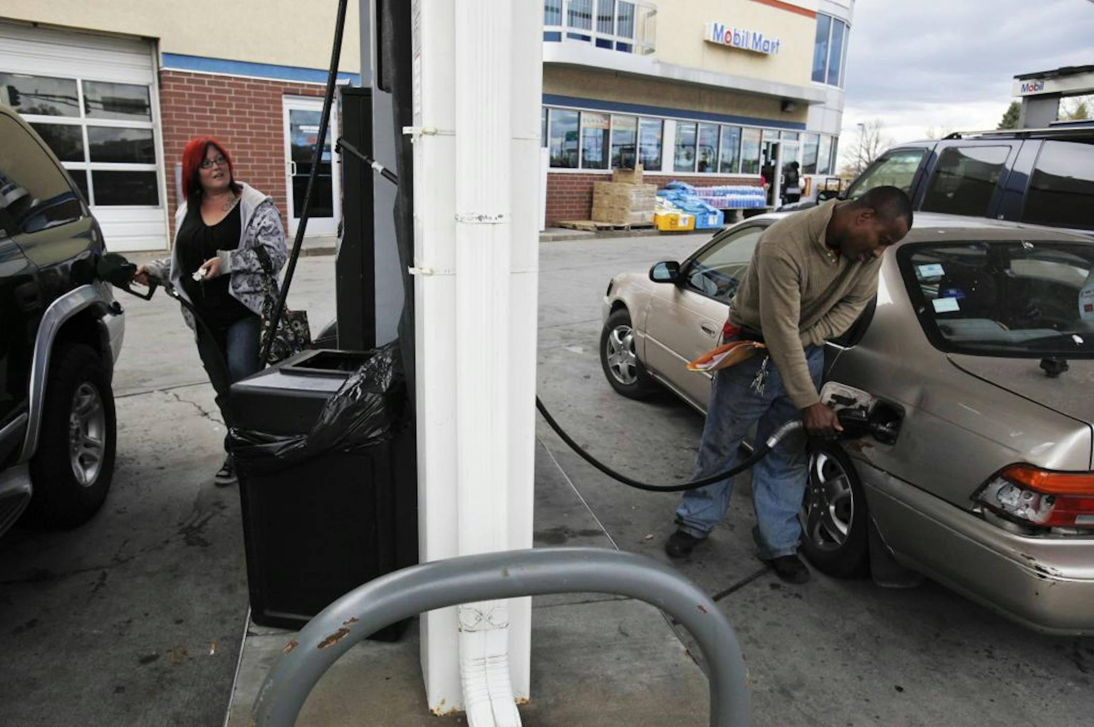 Sara Hendrickson of Coon Rapids, left, and Faki Kabto of St. Paul, right, filled up their vehicles with gas at Highway 10 Mobil in Coon Rapids, Oct. 26, 2011.