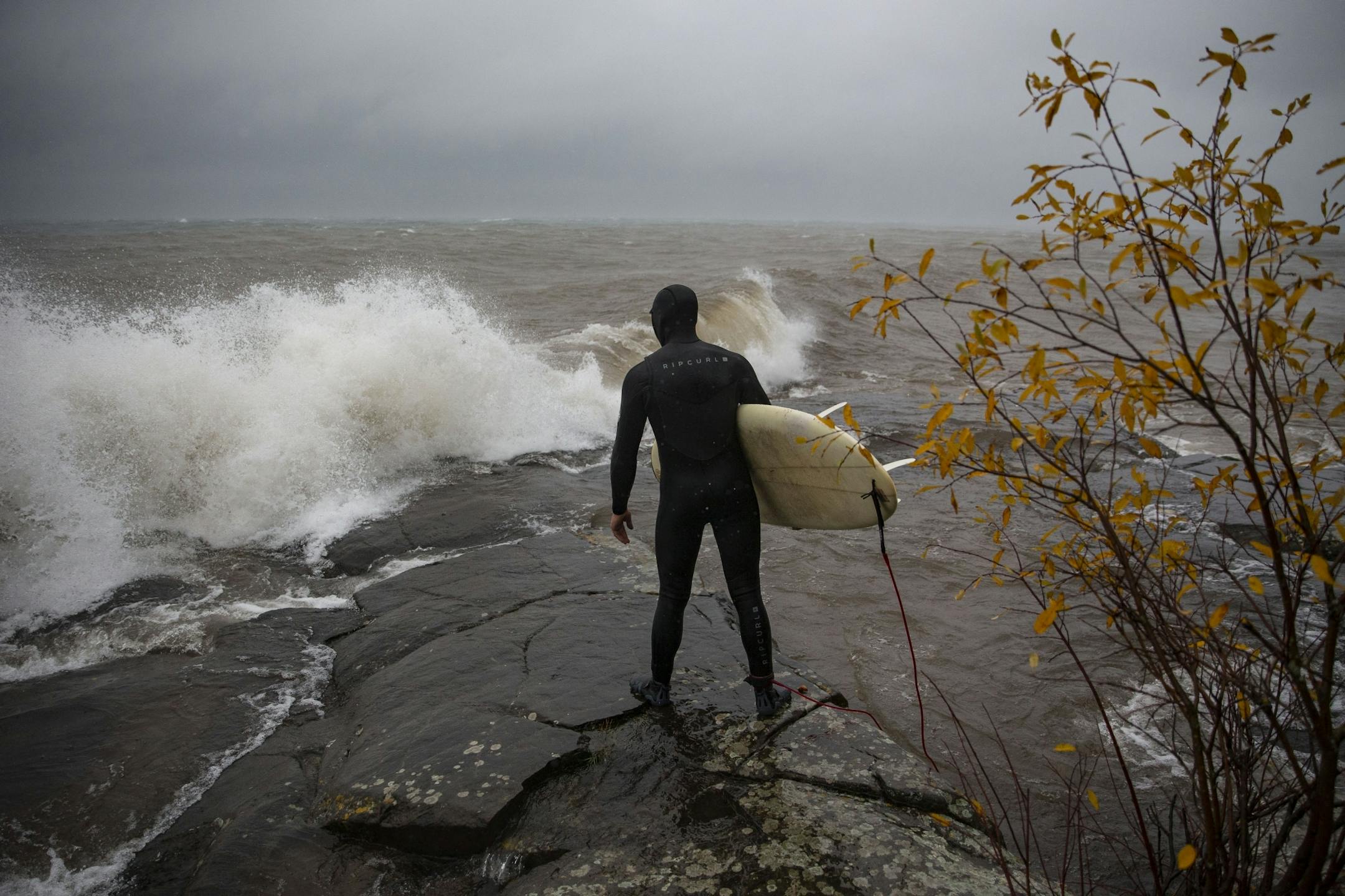 Kevin Milligan surveyed the waves and coastline before surfing on Monday. He was one of the first people out riding the massive waves of Lake Superior on Monday.
